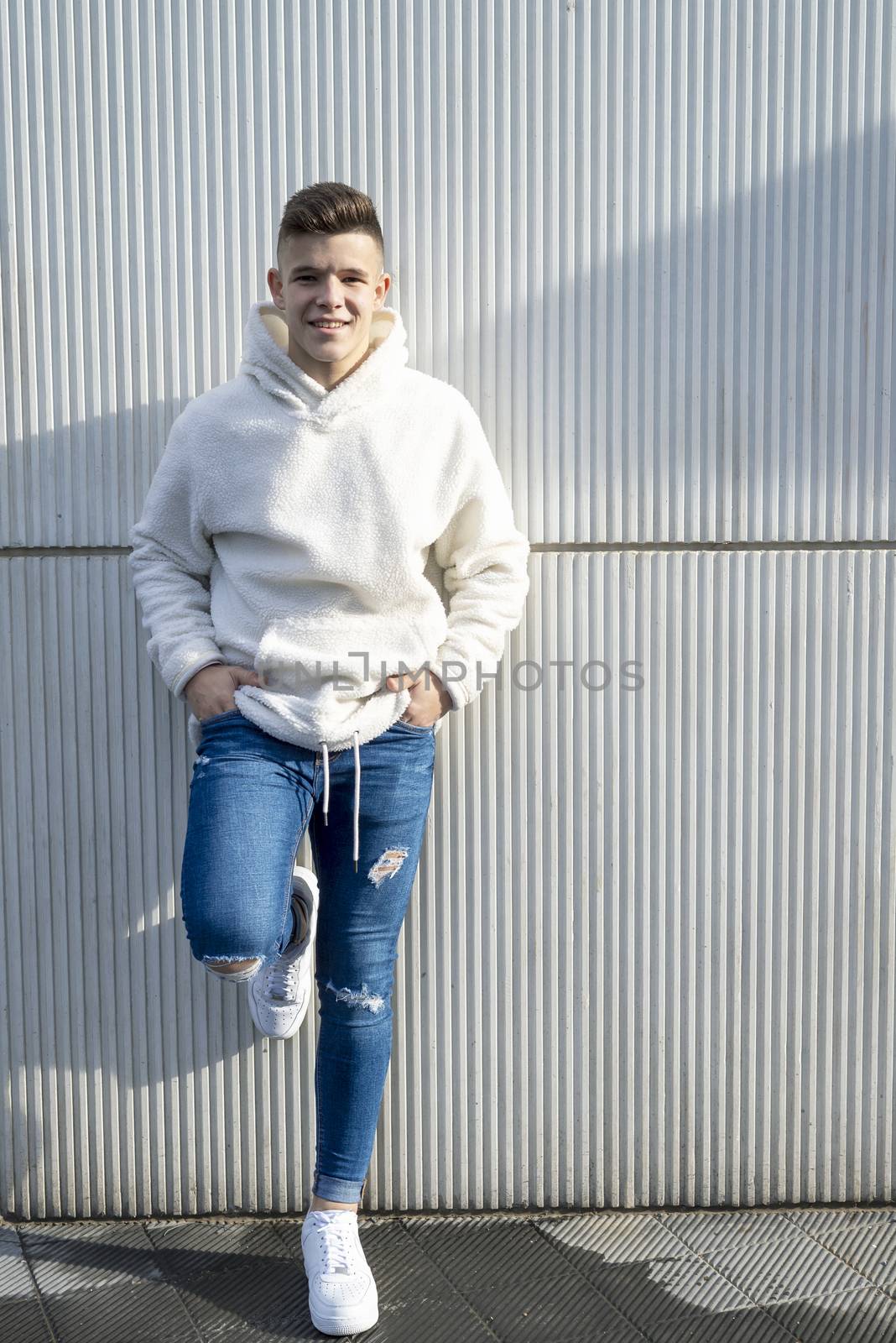 Portrait of young male with hands on pocket leaning on wall outdoors