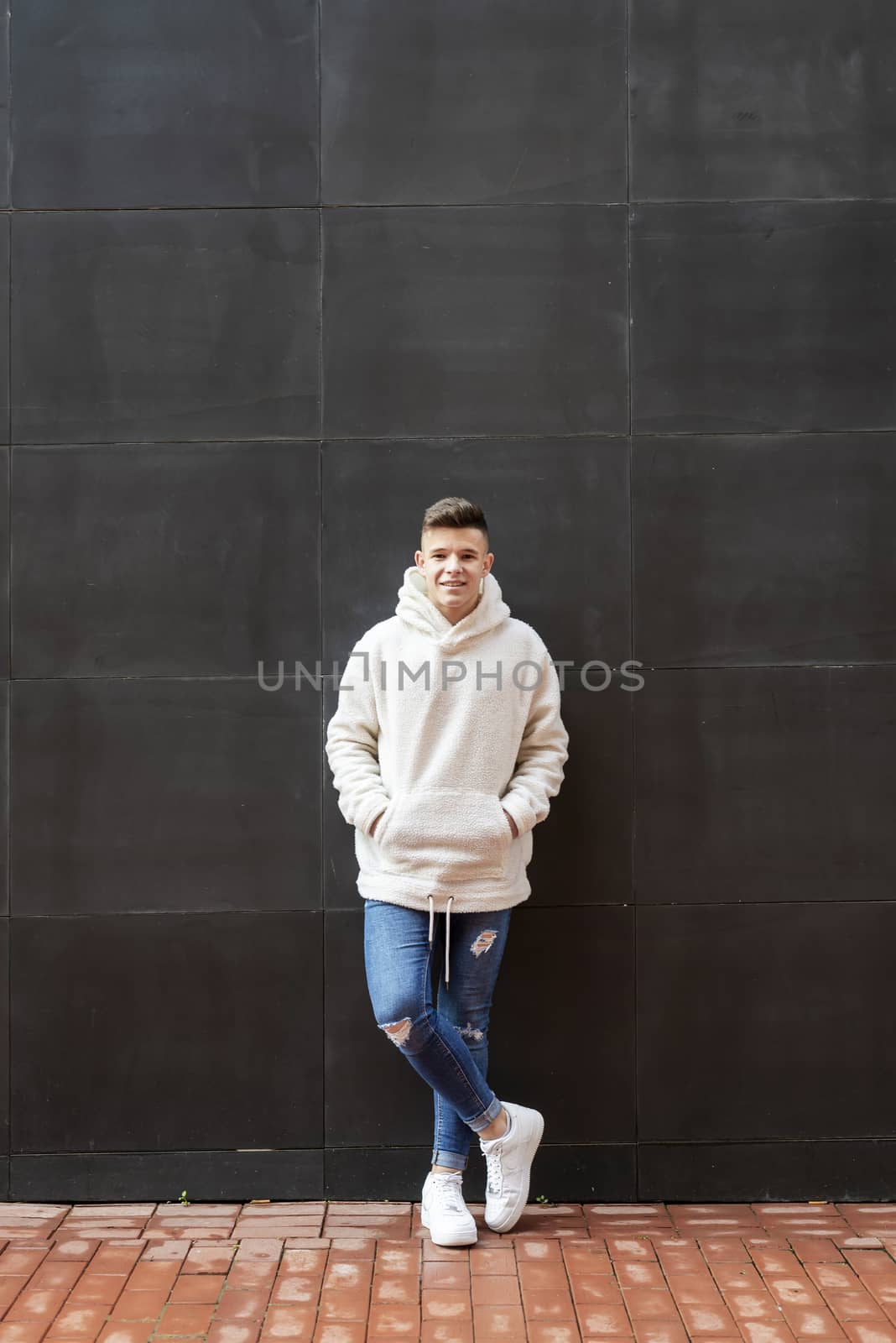 Portrait of young male with hands on pocket leaning on wall outdoors