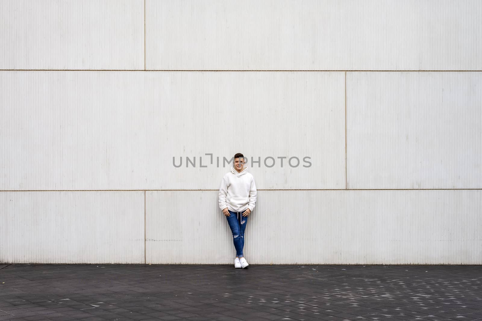 Portrait of young male with hands on pocket leaning on wall outdoors