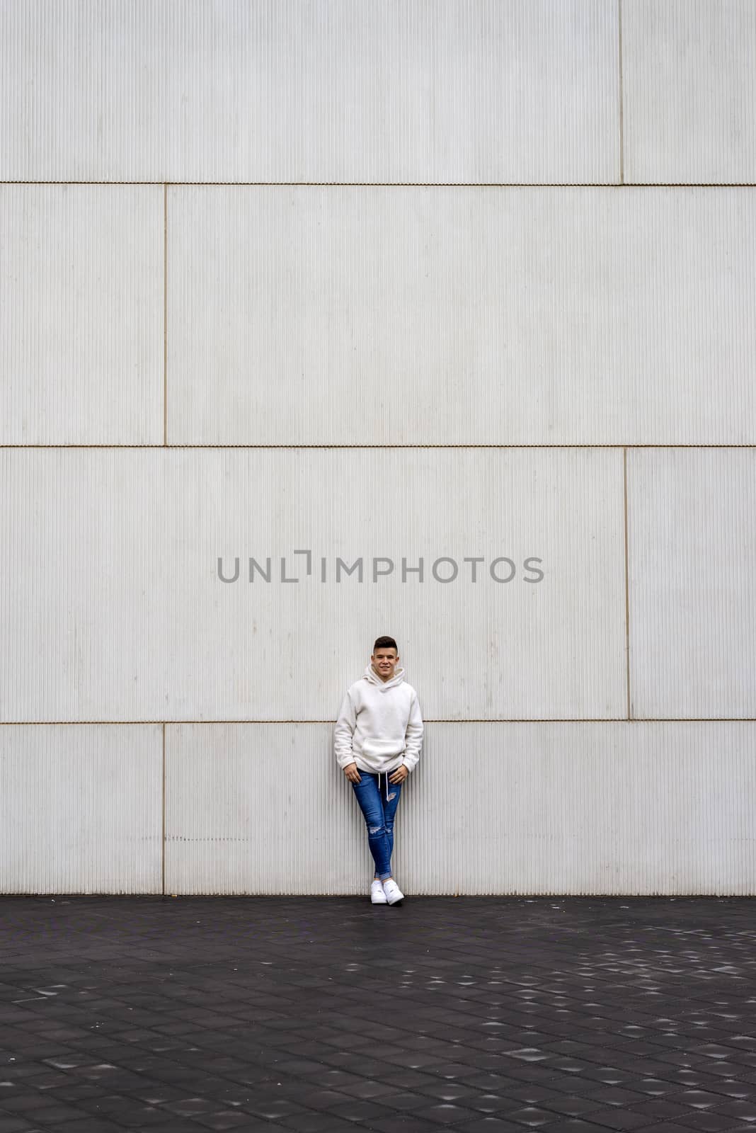 Portrait of young male with hands on pocket leaning on wall outdoors