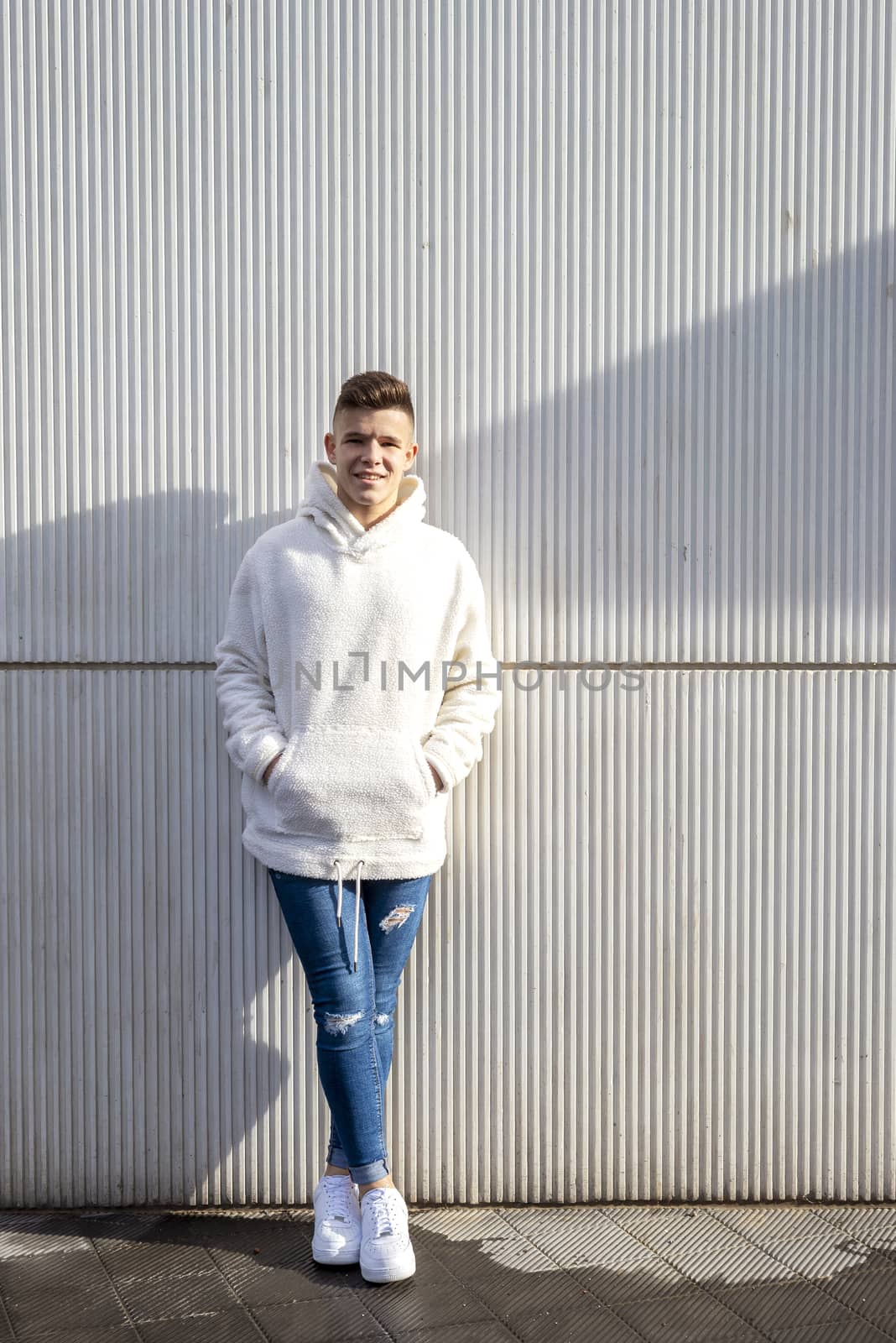 Portrait of young male with hands on pocket leaning on wall outdoors