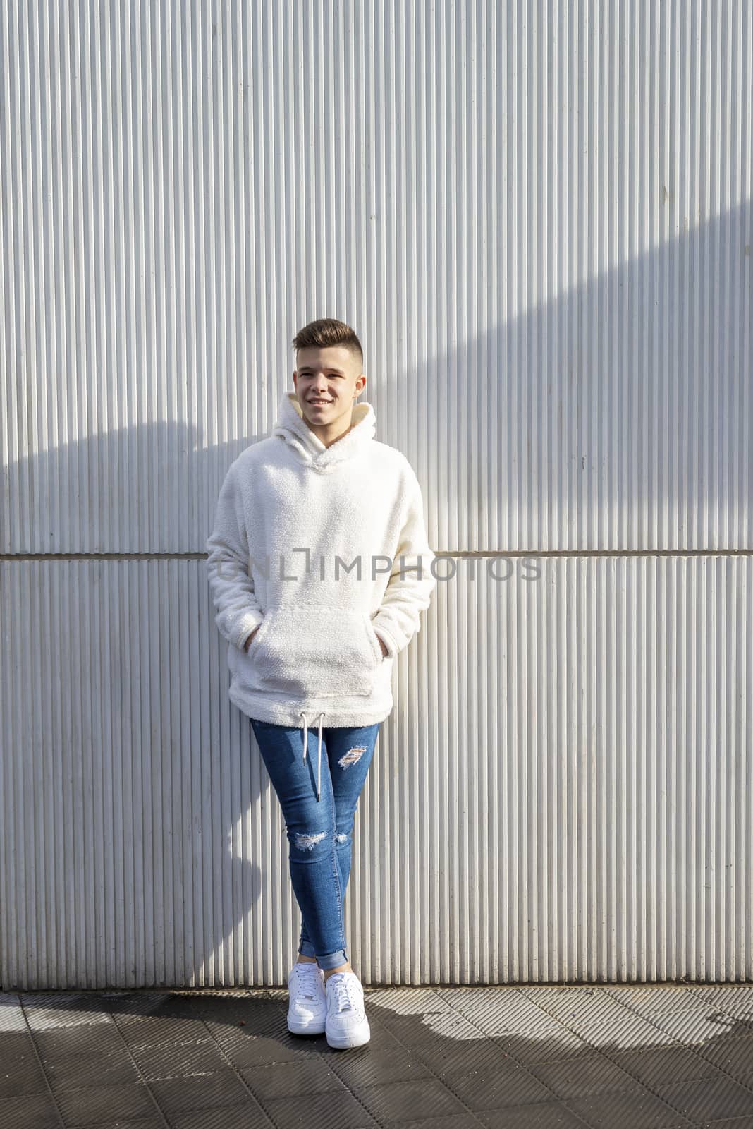 Portrait of young male with hands on pocket leaning on wall outdoors