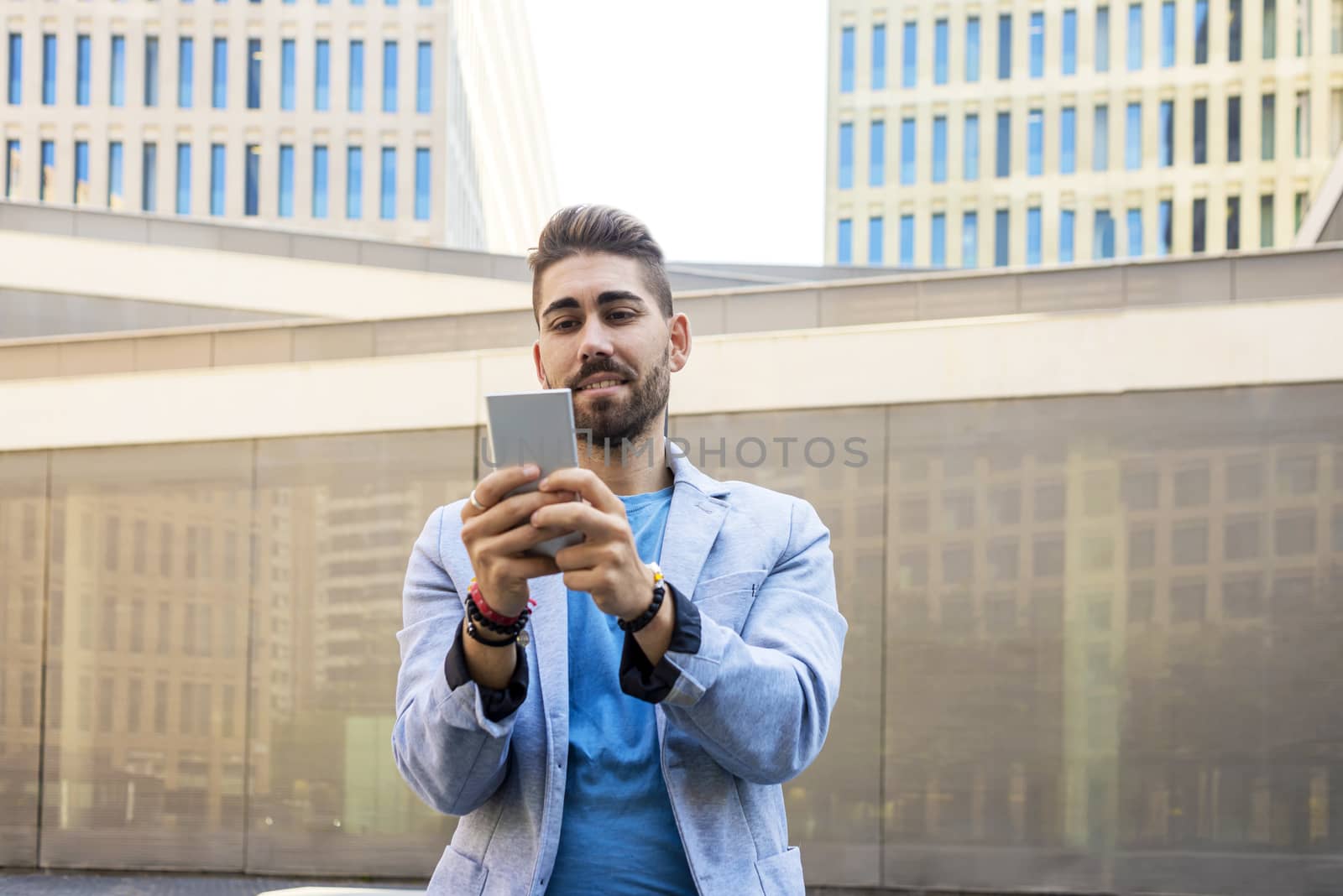 Portrait of Handsome bearded young man smiling when he is using his mobile phone by raferto1973