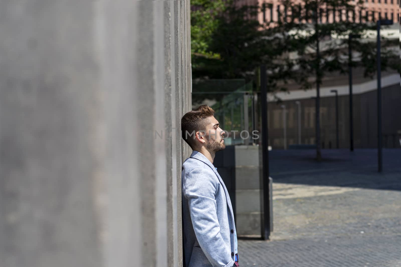 young bearded man leaning against wall and thinking