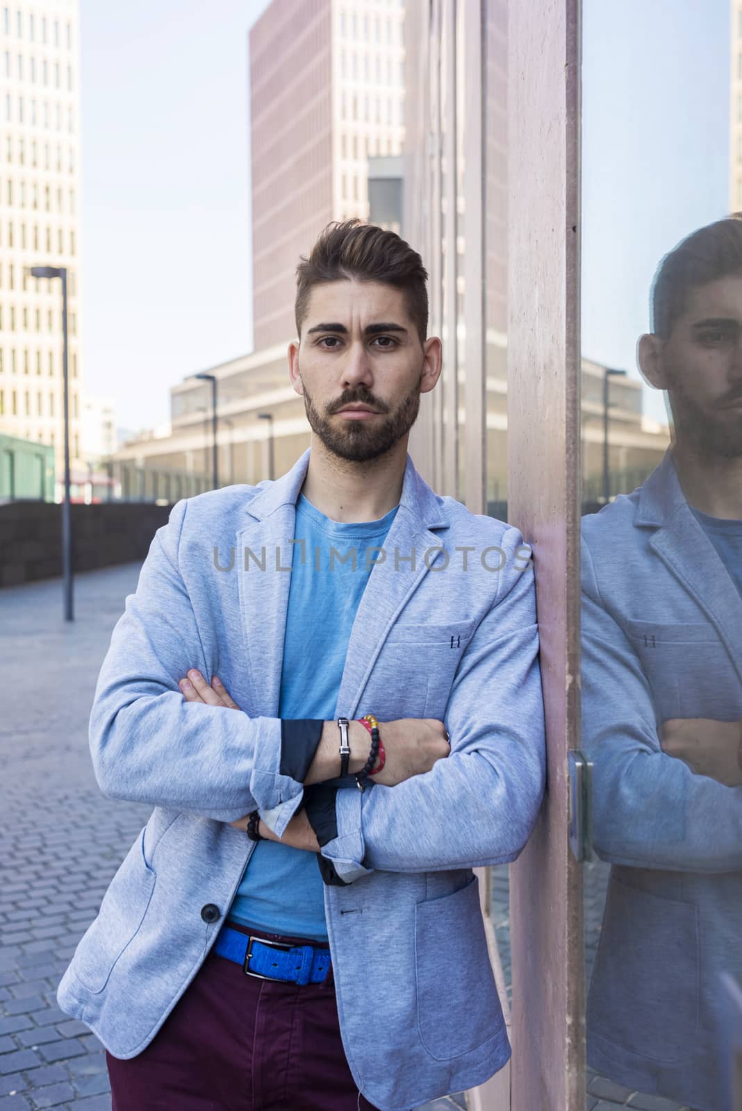 Young bearded man with crossed arms, model of fashion, in urban background wearing casual clothes