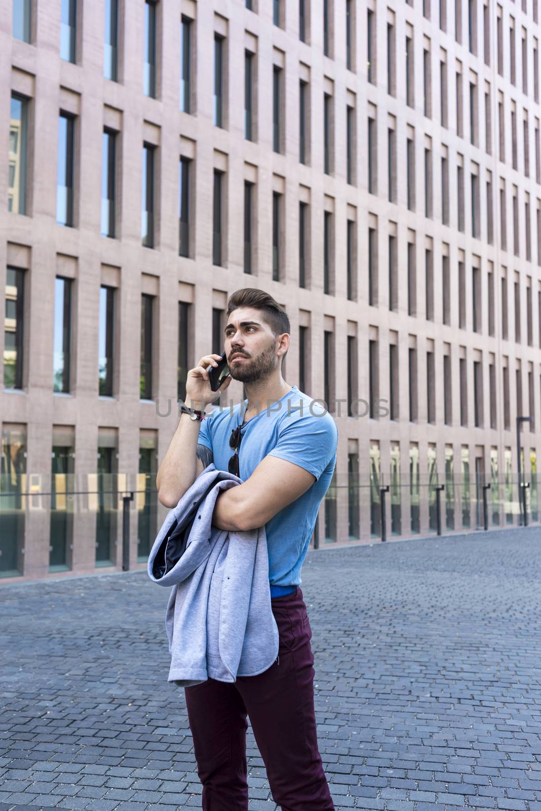 Young businessman talking on his phone outdoors by raferto1973