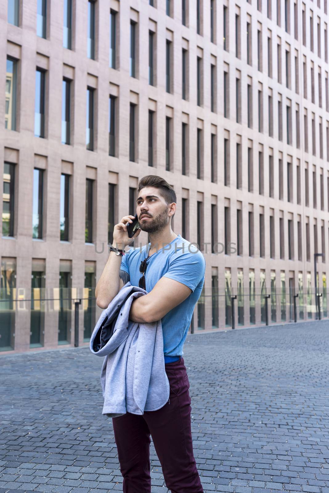 Portrait of cheerful modern businessman speaking by phone and smiling while standing outdoors