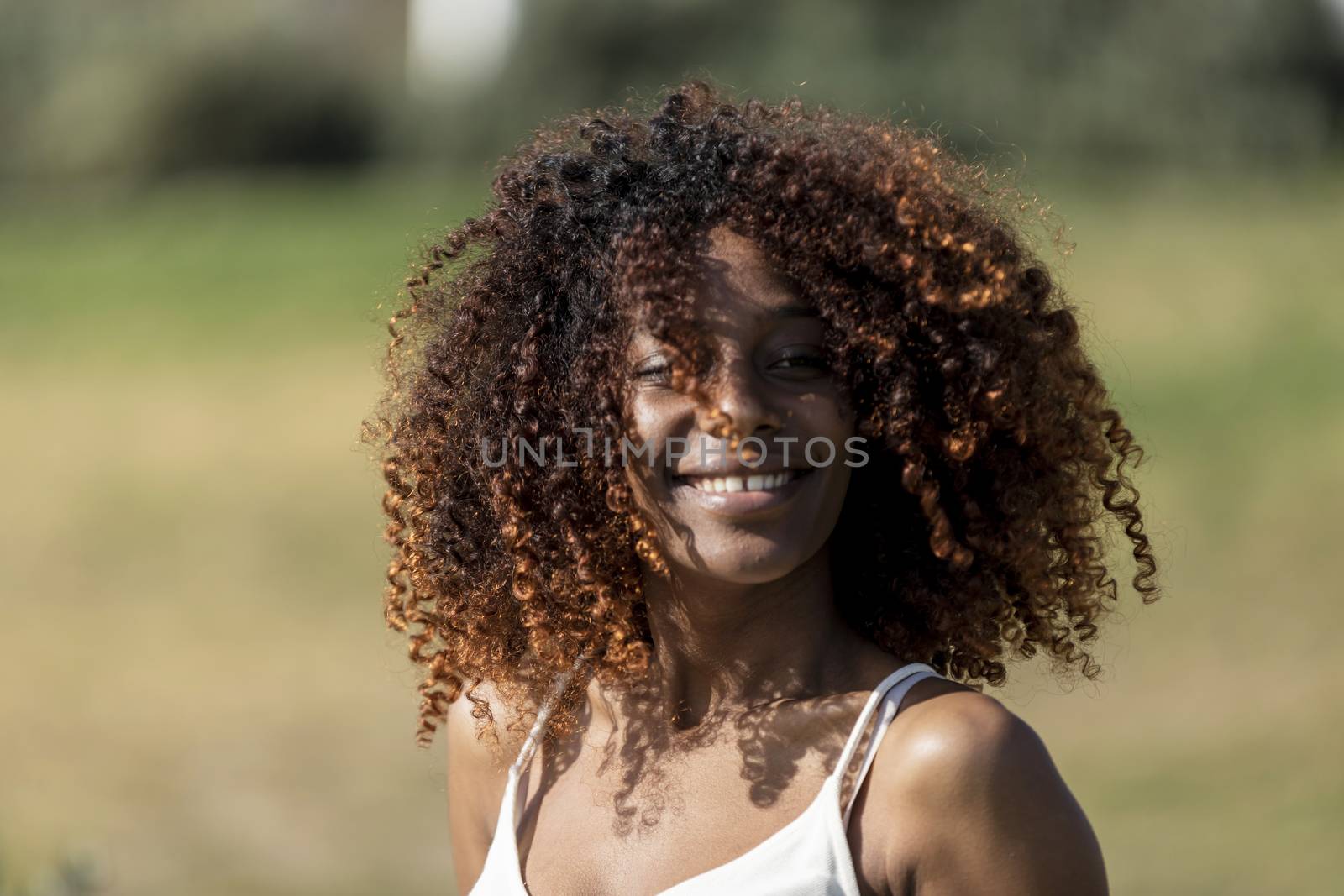 Afro american woman with white dress sitting on grass in a park in sunny day