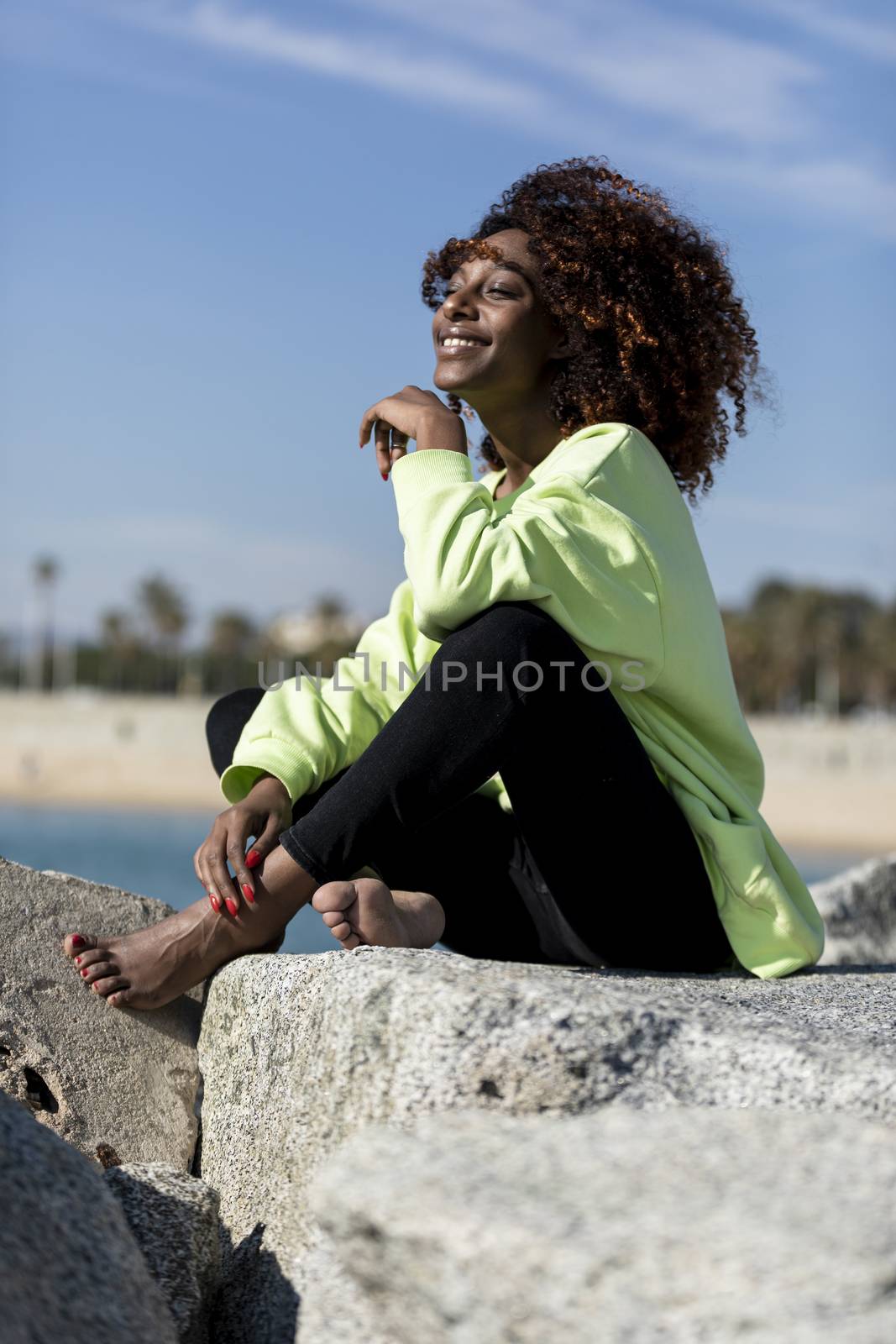 Portrait of a Beautiful afro american woman sitting on shore in a sunny day