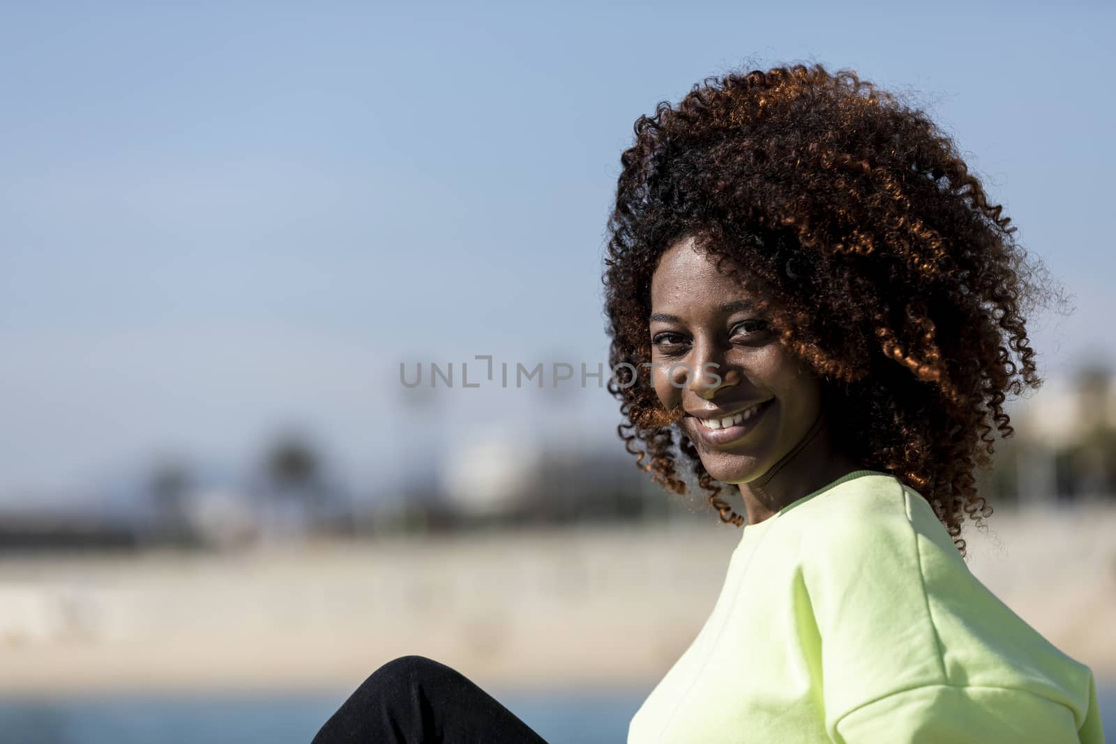 Portrait of a Beautiful afro american woman sitting on shore in a sunny day