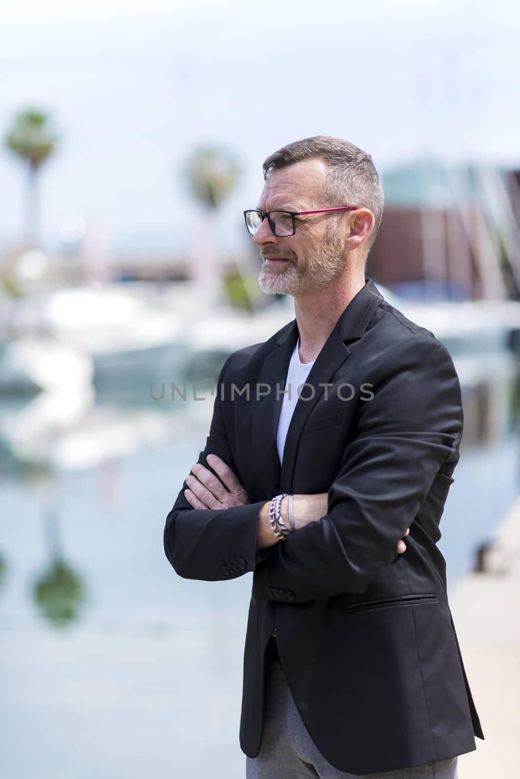 Businessman standing in the city arms crossed while looking away and smiling