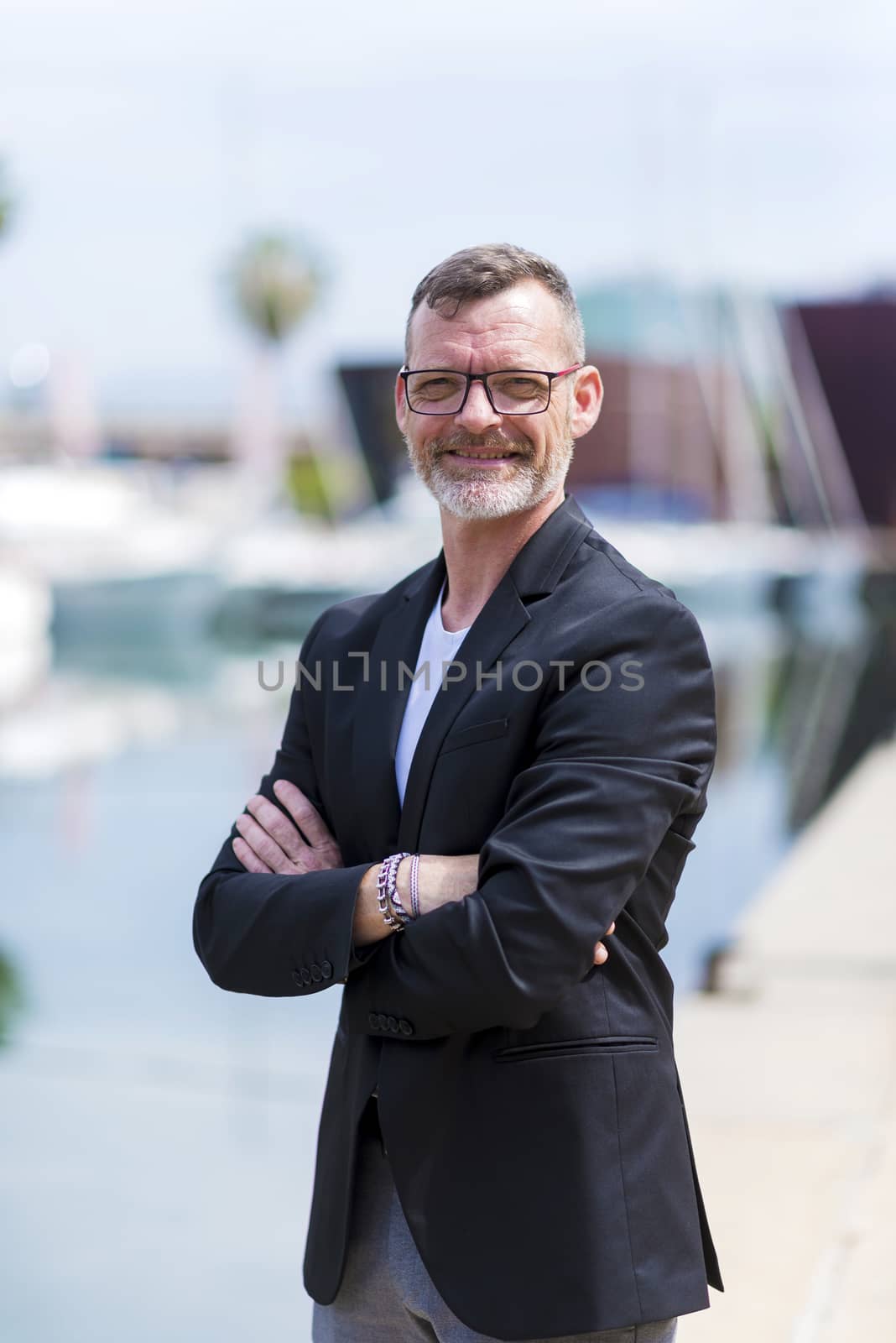 Businessman standing in the city arms crossed while looking camera and smiling
