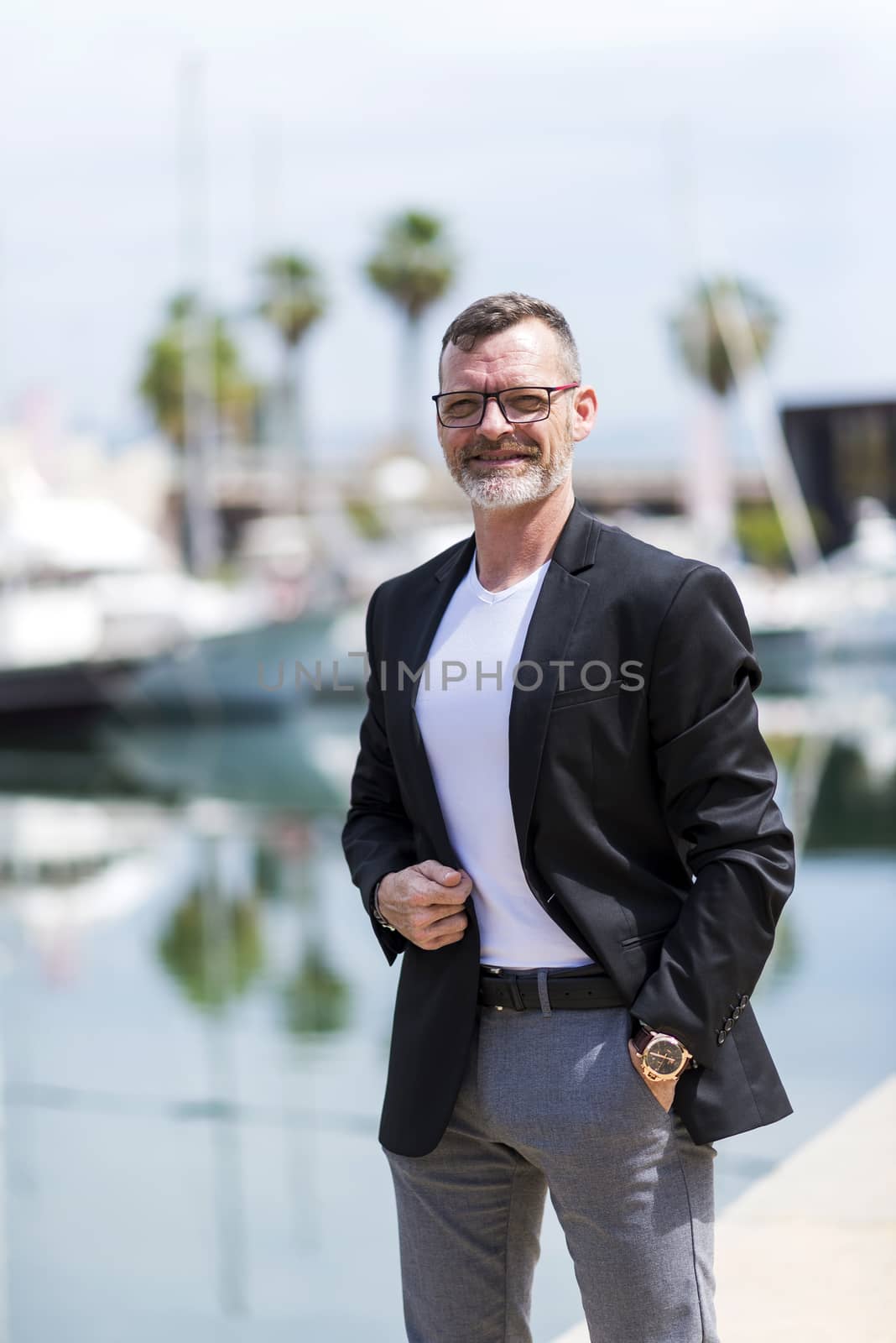 Businessman standing in the city hand on pocket while looking camera and smiling.