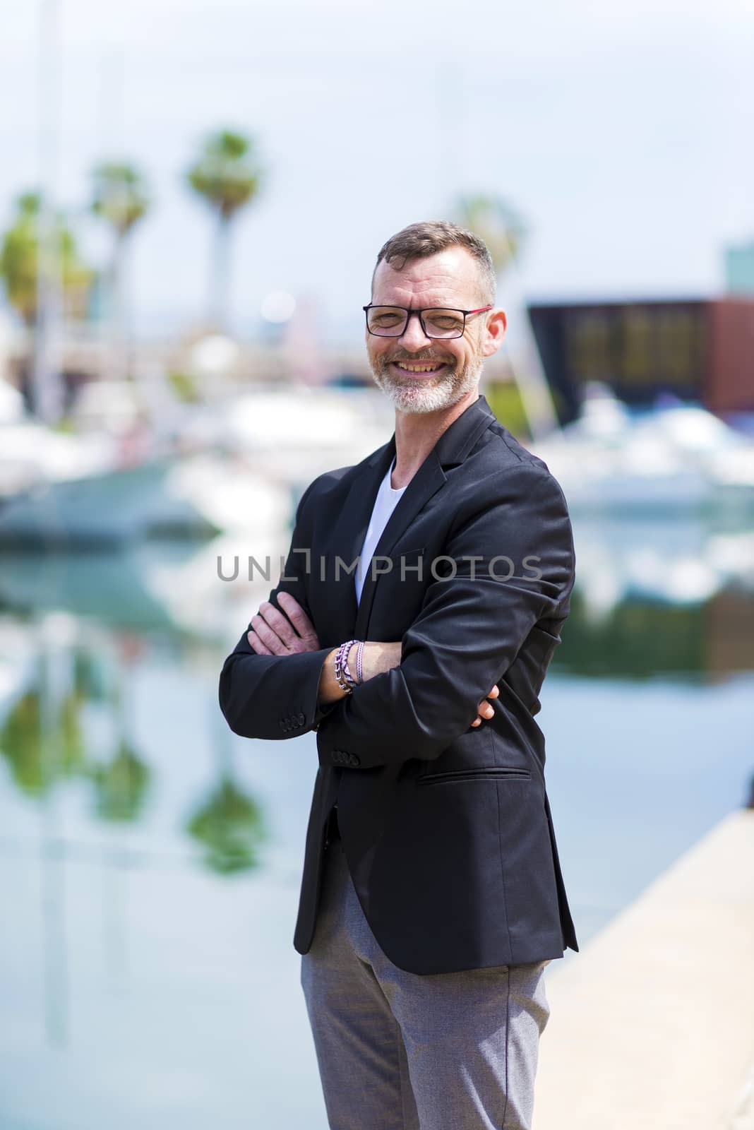 Businessman standing in the city arms crossed while looking camera and smiling