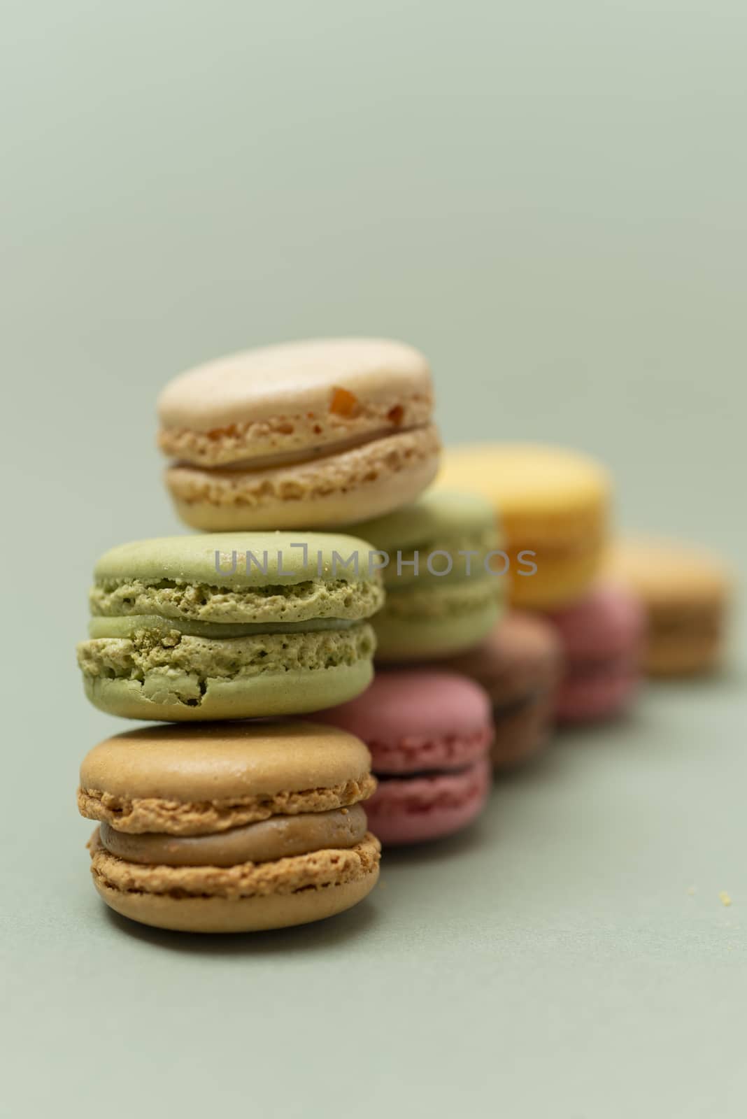 Vintage pastel colored French macaroons or macarons on green background