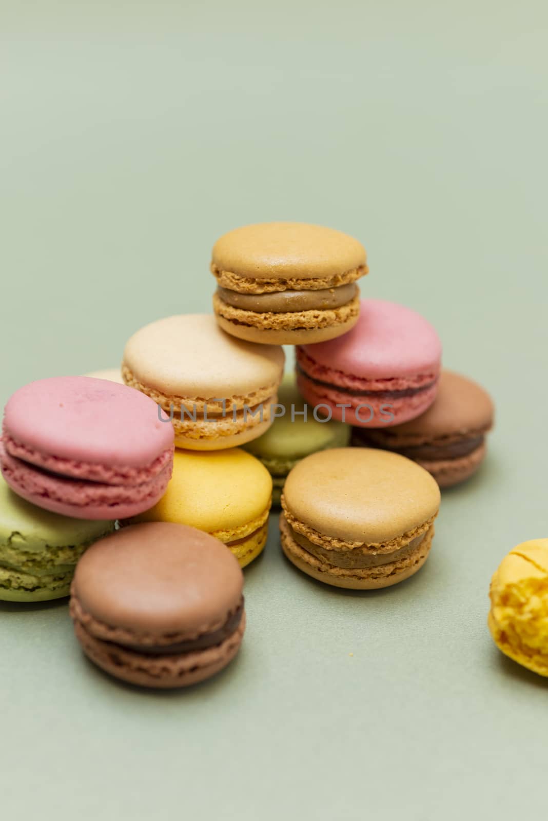 Vintage pastel colored French macaroons or macarons on green background