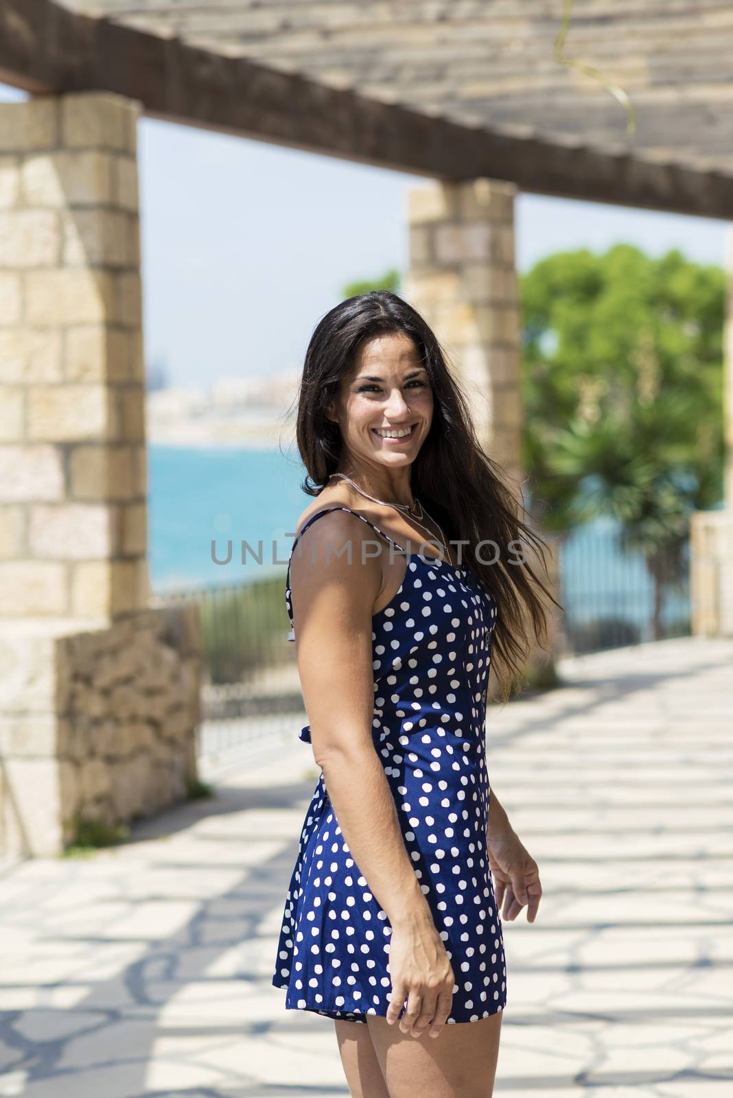 Beautiful smiling woman in blue dress standing outdoors while looking camera
