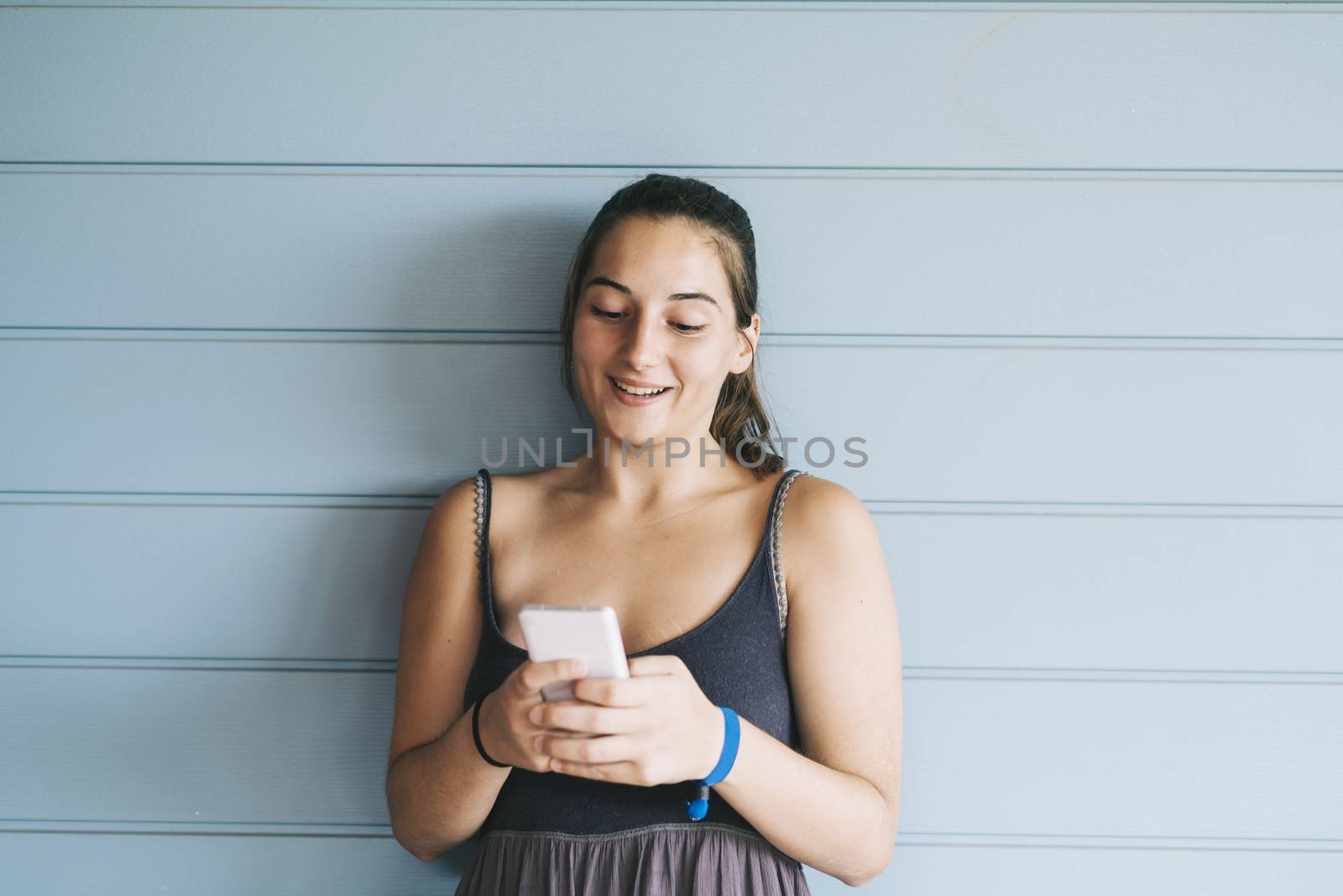 Beautiful woman leaning on a wood wall while using a smartphone