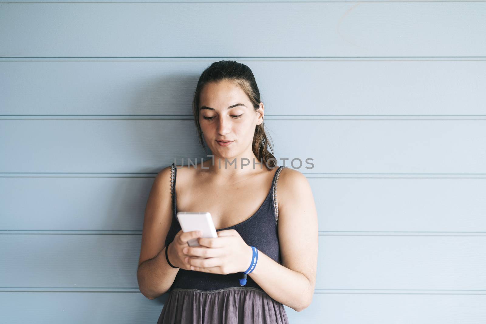 Beautiful woman leaning on a wood wall while using a smartphone