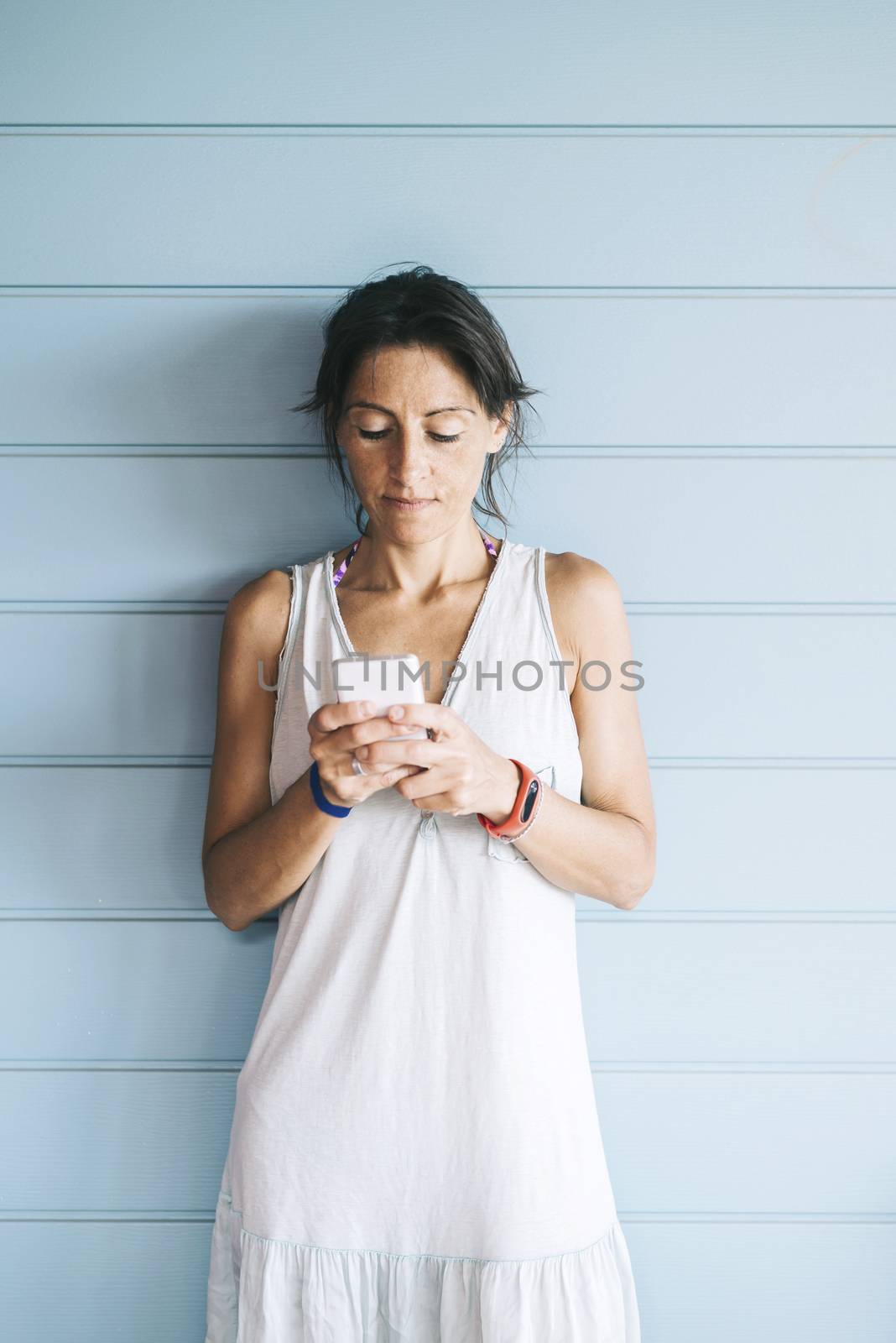 Beautiful woman leaning on a wood wall while using a smartphone