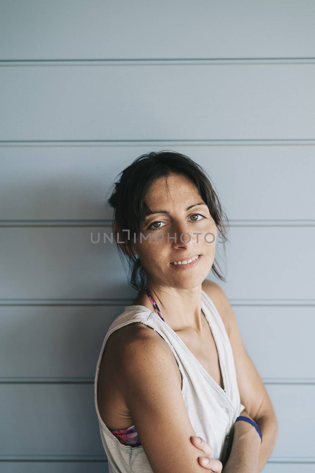 Hispanic woman with summer dress and ponytail while leaning on wood wall