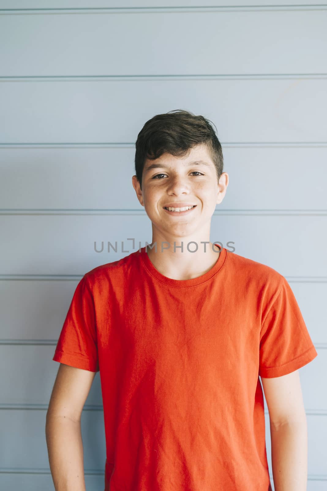 Portrait of a cheerful male teen leaning on wood wall while looking camera by raferto1973