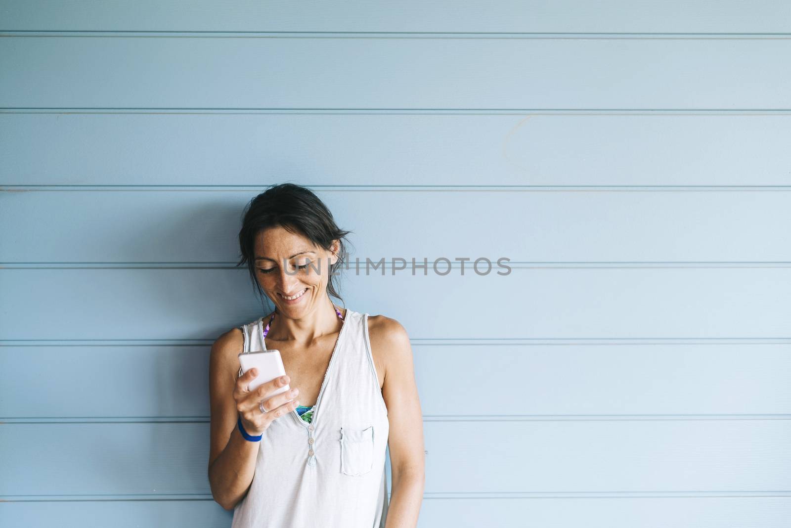 Beautiful woman leaning on a wood wall while using a smartphone