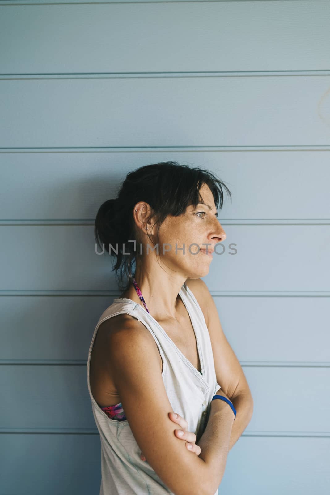 Hispanic woman with summer dress and ponytail while leaning on wood wall