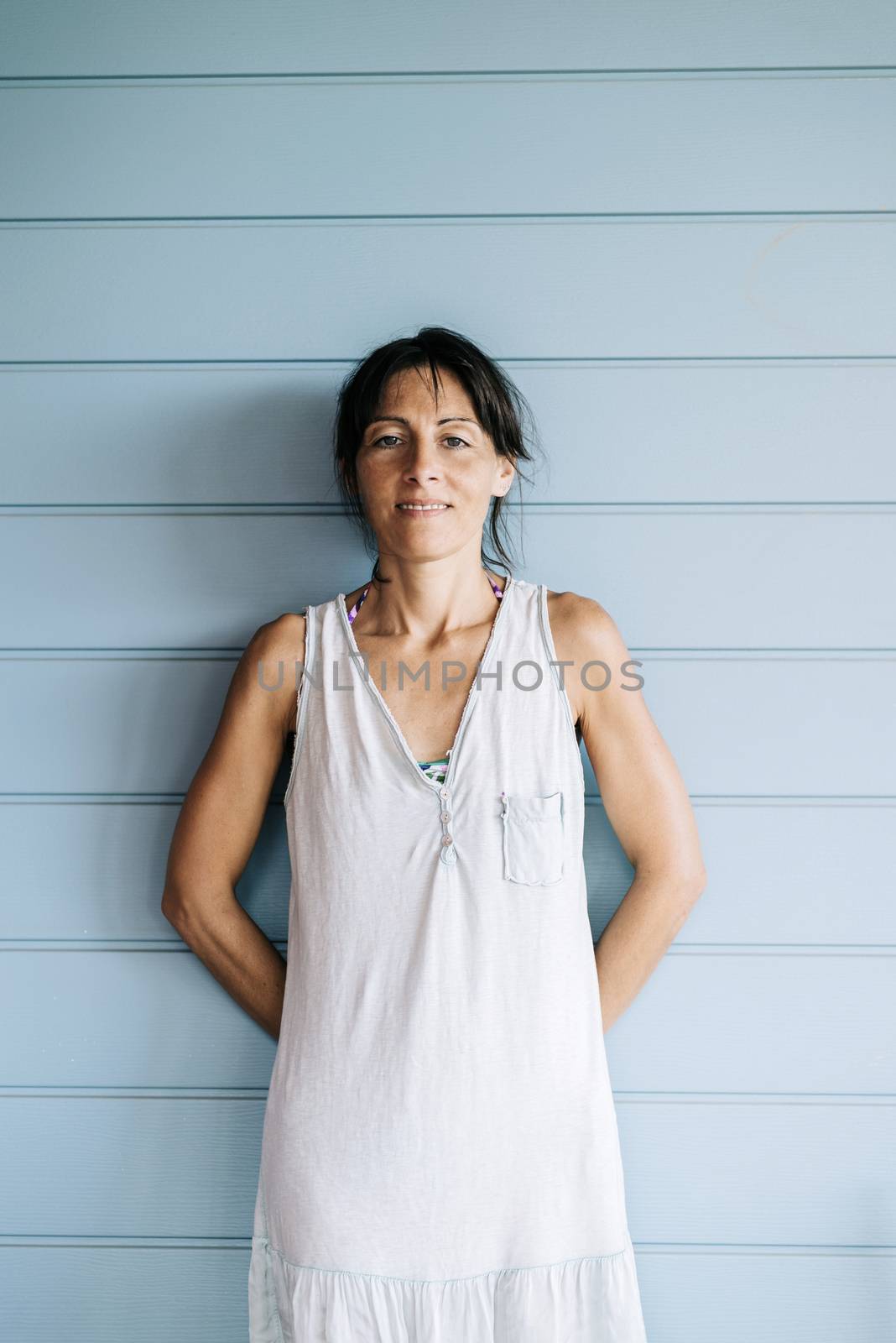 Hispanic woman with summer dress and ponytail while leaning on wood wall