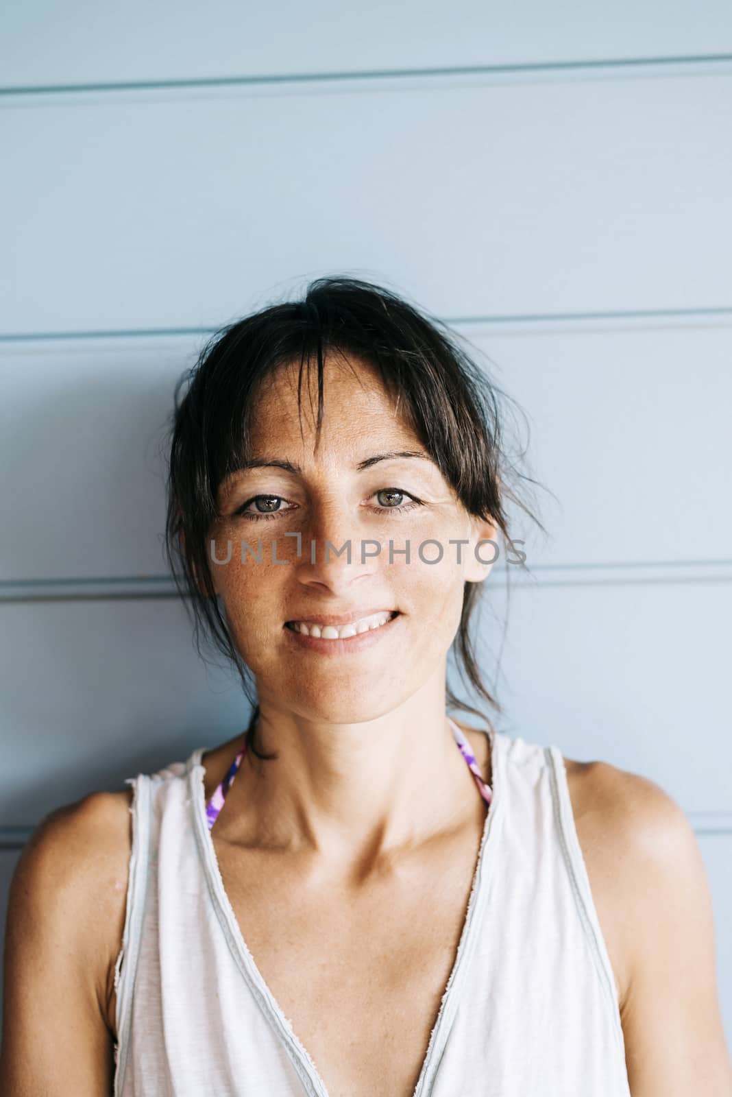 Hispanic woman with summer dress and ponytail while leaning on wood wall