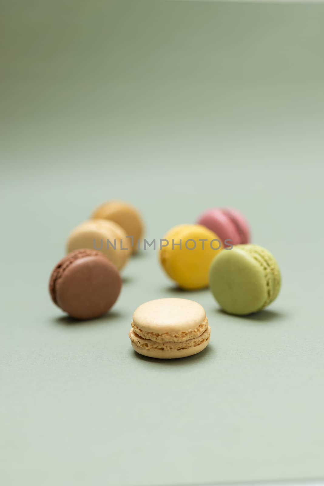 Colored tasty  macaroons over a green background.