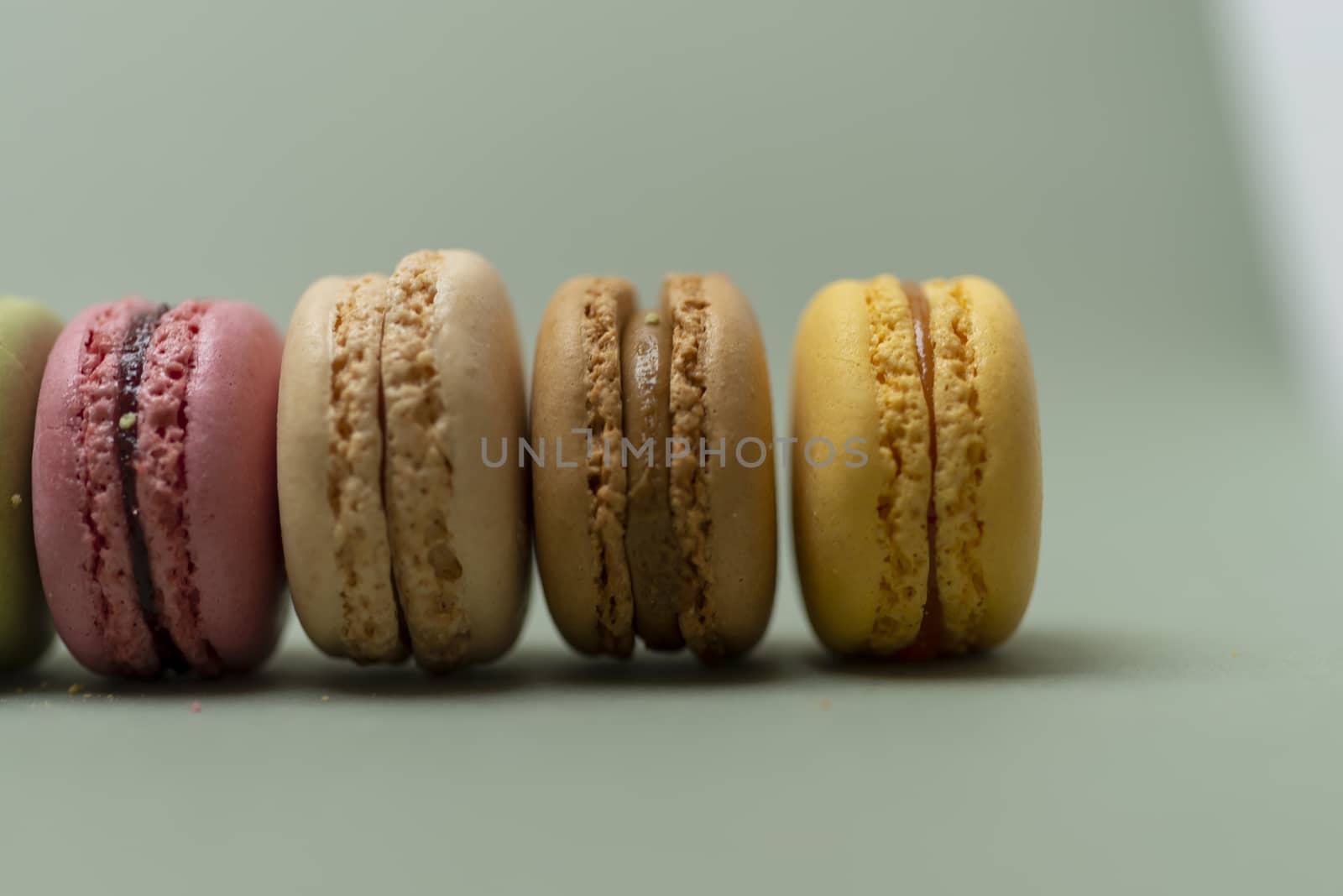 Colored tasty  macaroons over a green background.