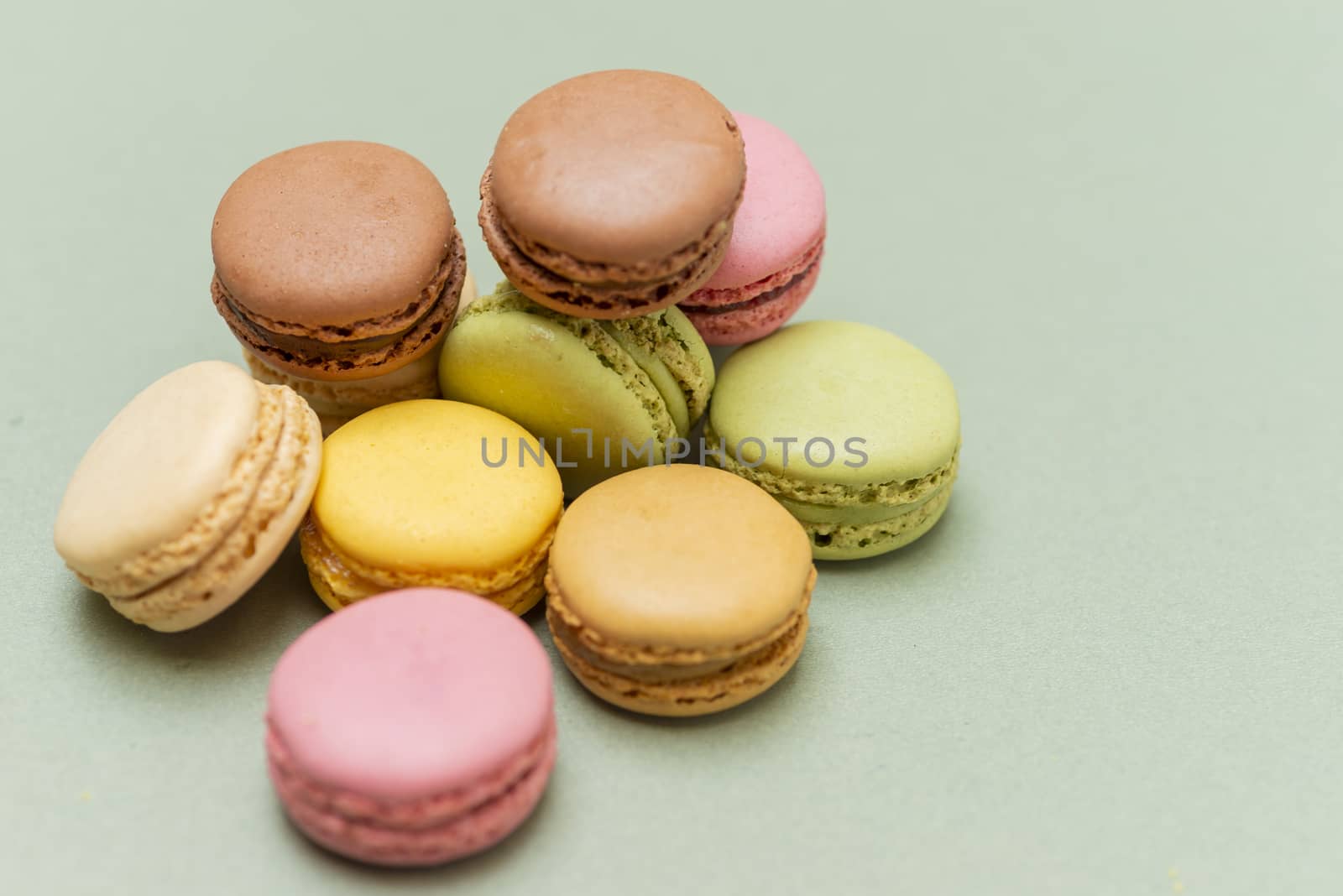 Colored tasty  macaroons over a green background.
