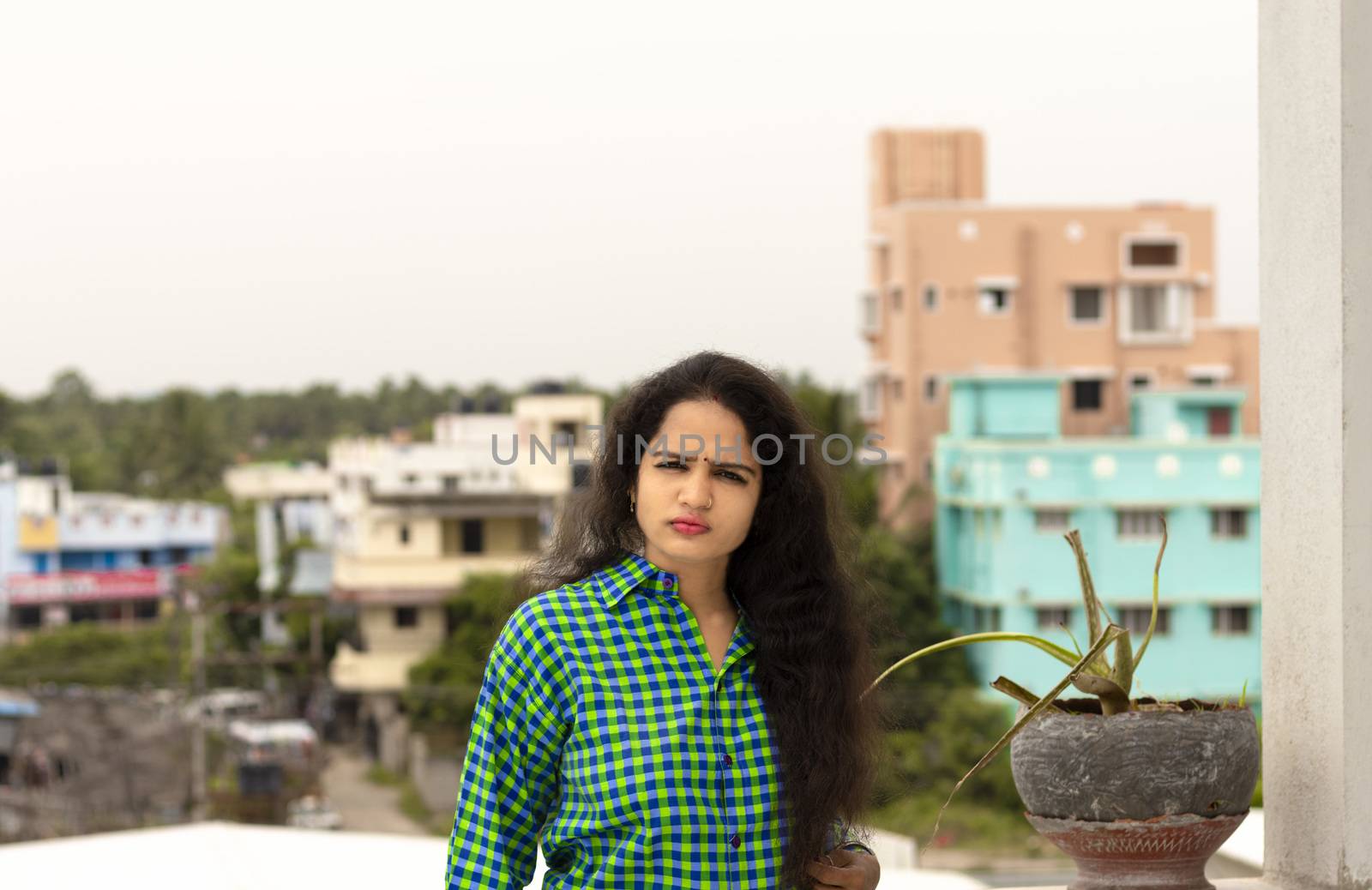 A beautiful Indian woman and wearing a green shirt and the back of Chennai City blur background