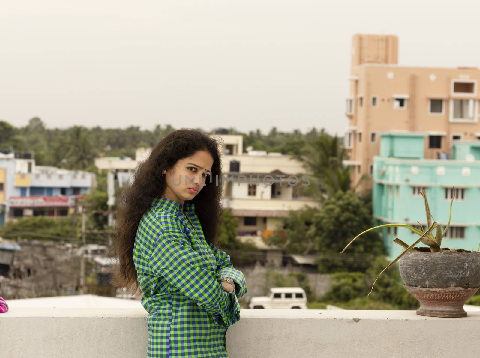 A young Hindu Indian woman standing in an open environment above the roof of the house and happily photographed beautiful and wearing a green shirt