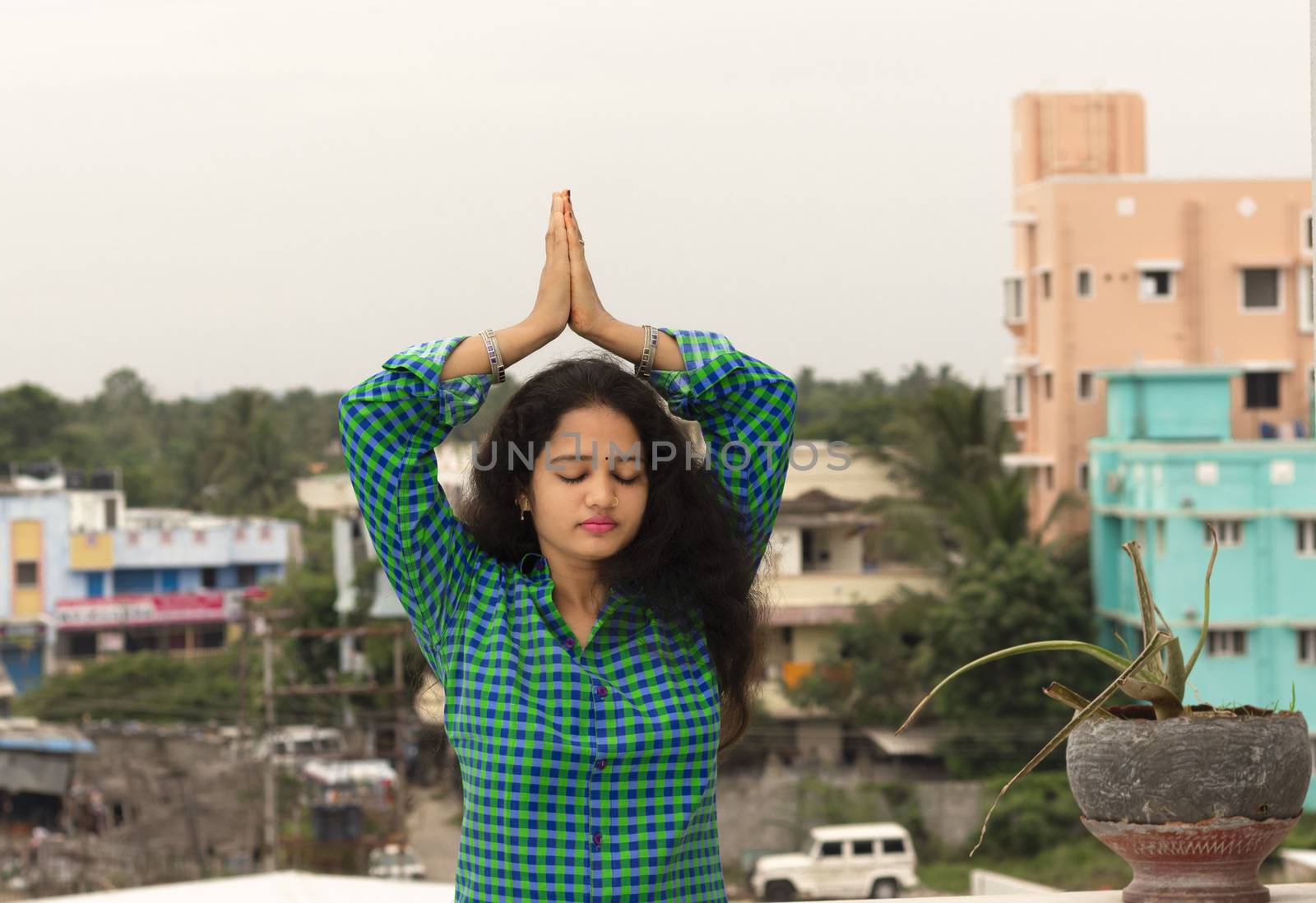 A young Hindu woman standing in an open environment, closed her eyes and asked for a vow to attach her hands to the Sun God above the head.