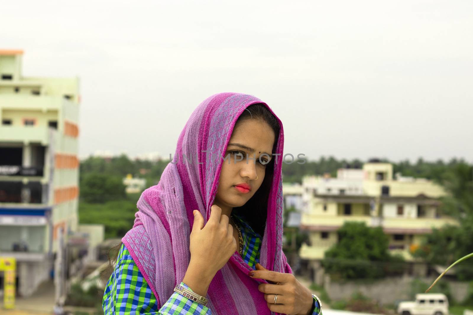 A young beautiful Hindu girl with a green shirt and a colorful scarf on the head and backwards blur building of Chennai City