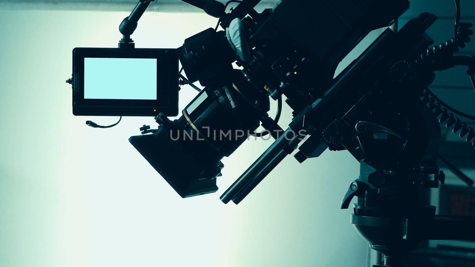 Silhouette images of video camera in tv commercial studio production which operating or shooting by cameraman and film crew team in set and prop on professional crane and tripod for easy to pan tilt or shift