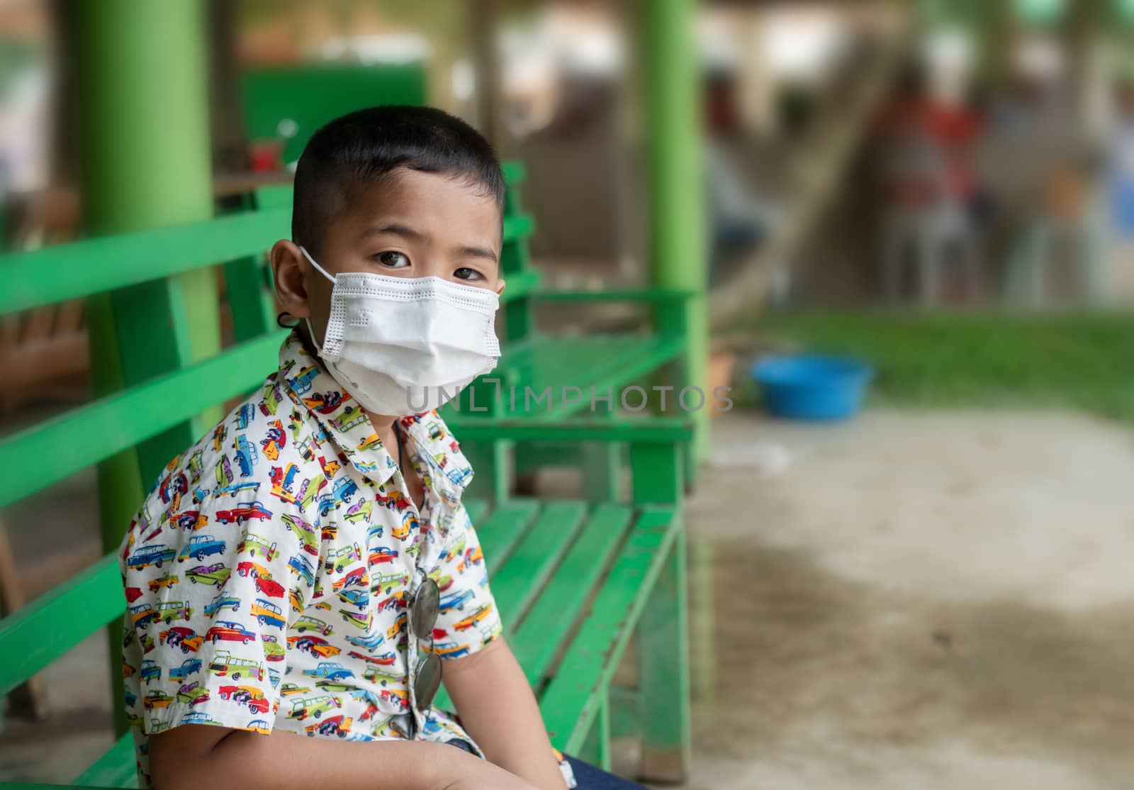 Boy wearing a mask Sit on a bench