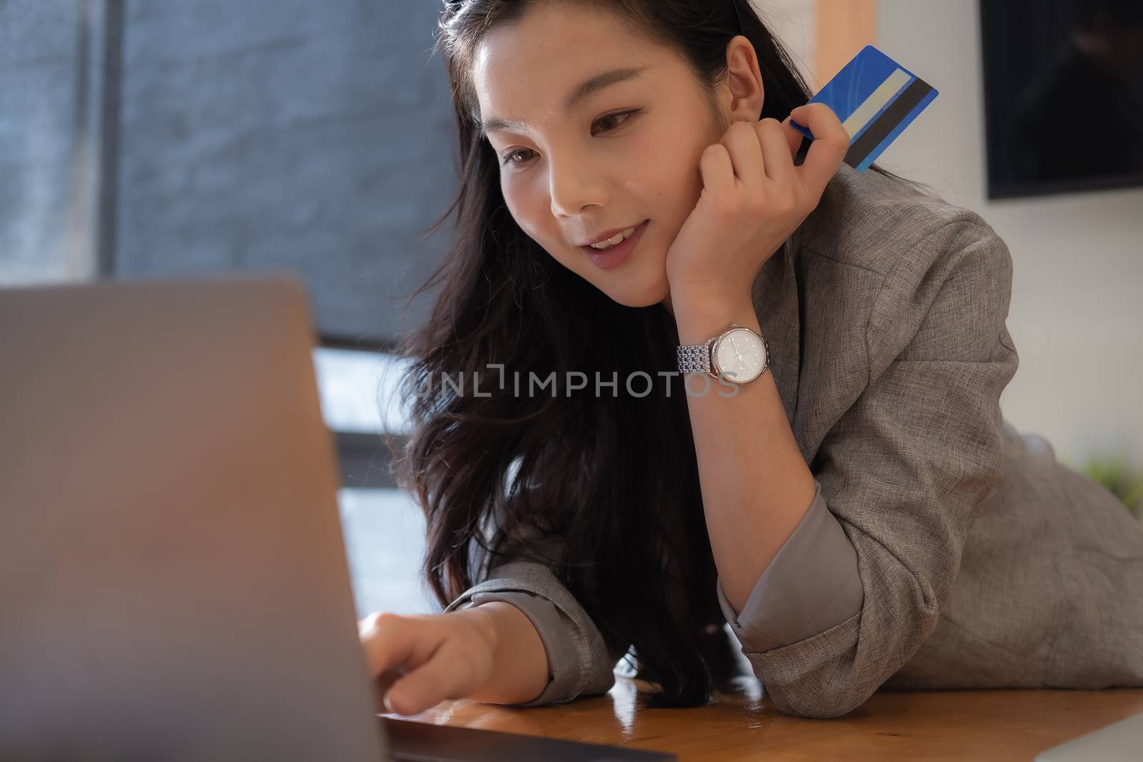 Asian woman makes a purchase on the Internet on the laptop computer with credit card.