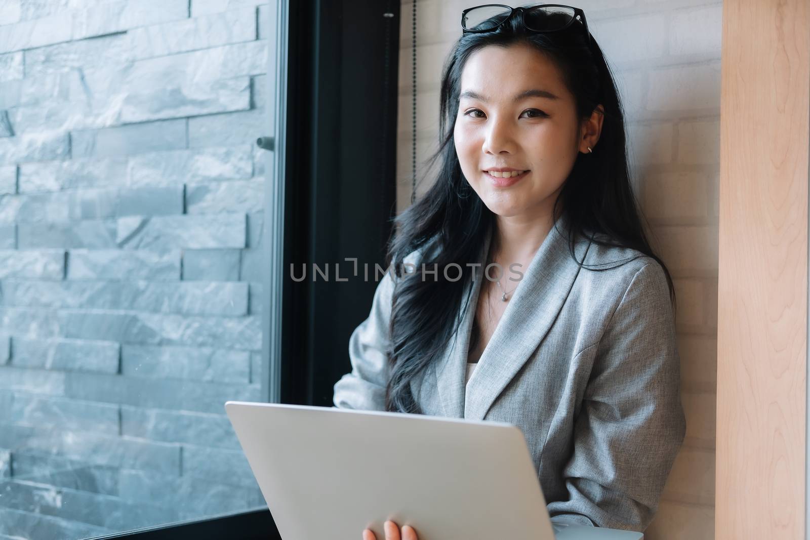 Portrait of smiling millennial businesswoman holding laptop computer looking at camera.
