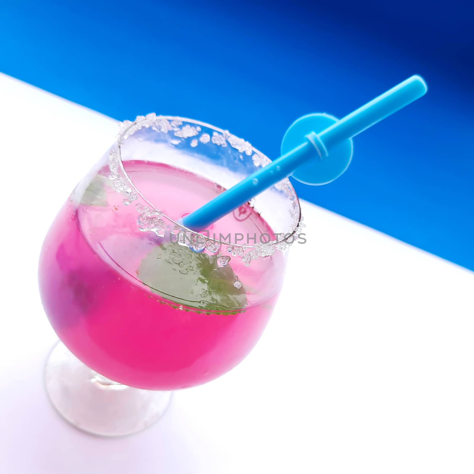 Colorful pink juice added with lemon juice and straw inside it plated beautifully in white and blue background and good for immunity booster