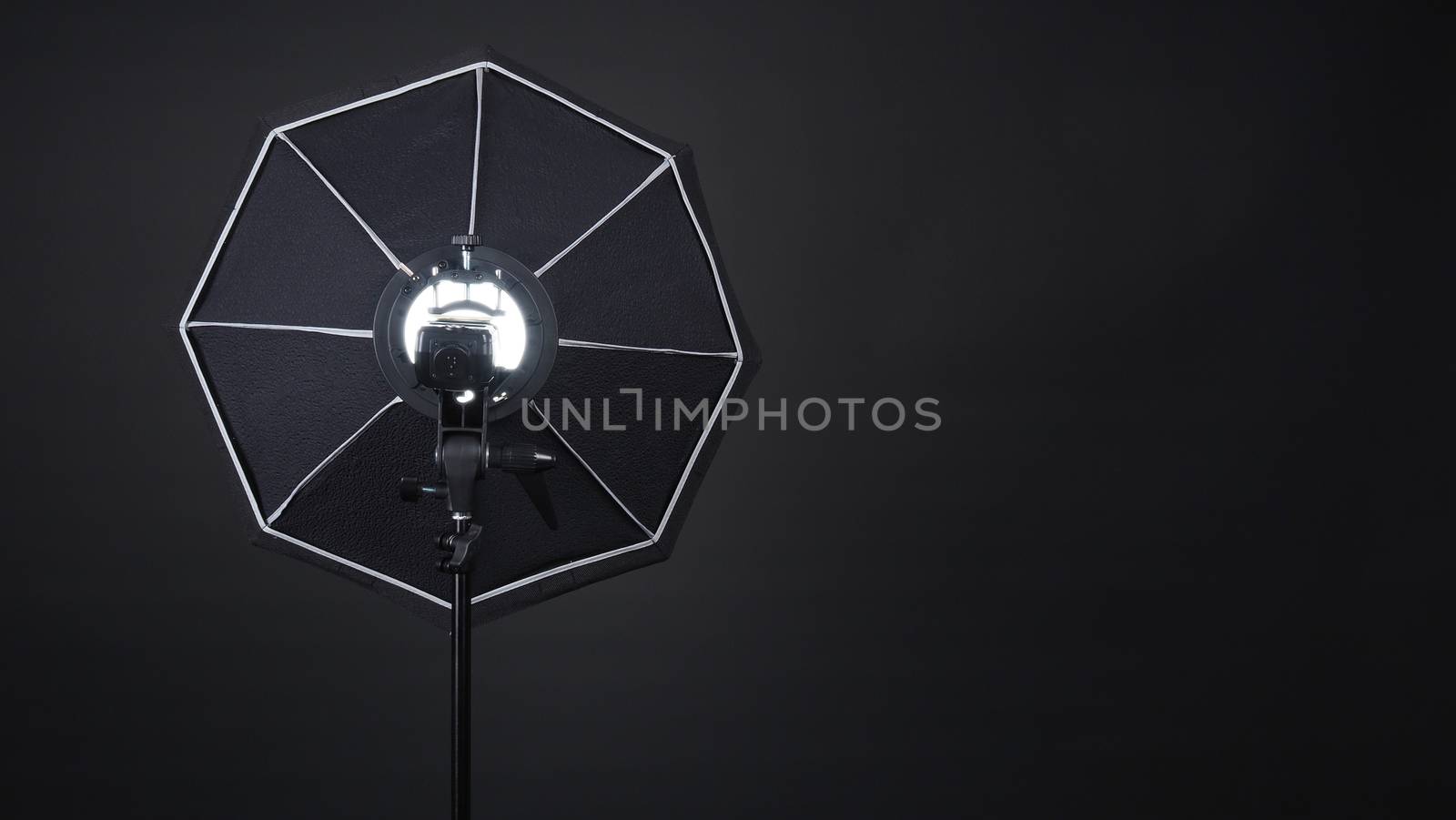 Professional photo studio soft box and flash on the tripod for stillphoto or video production which ready for shape the light for softer, harder or sharper by crew team before shooting on black background.