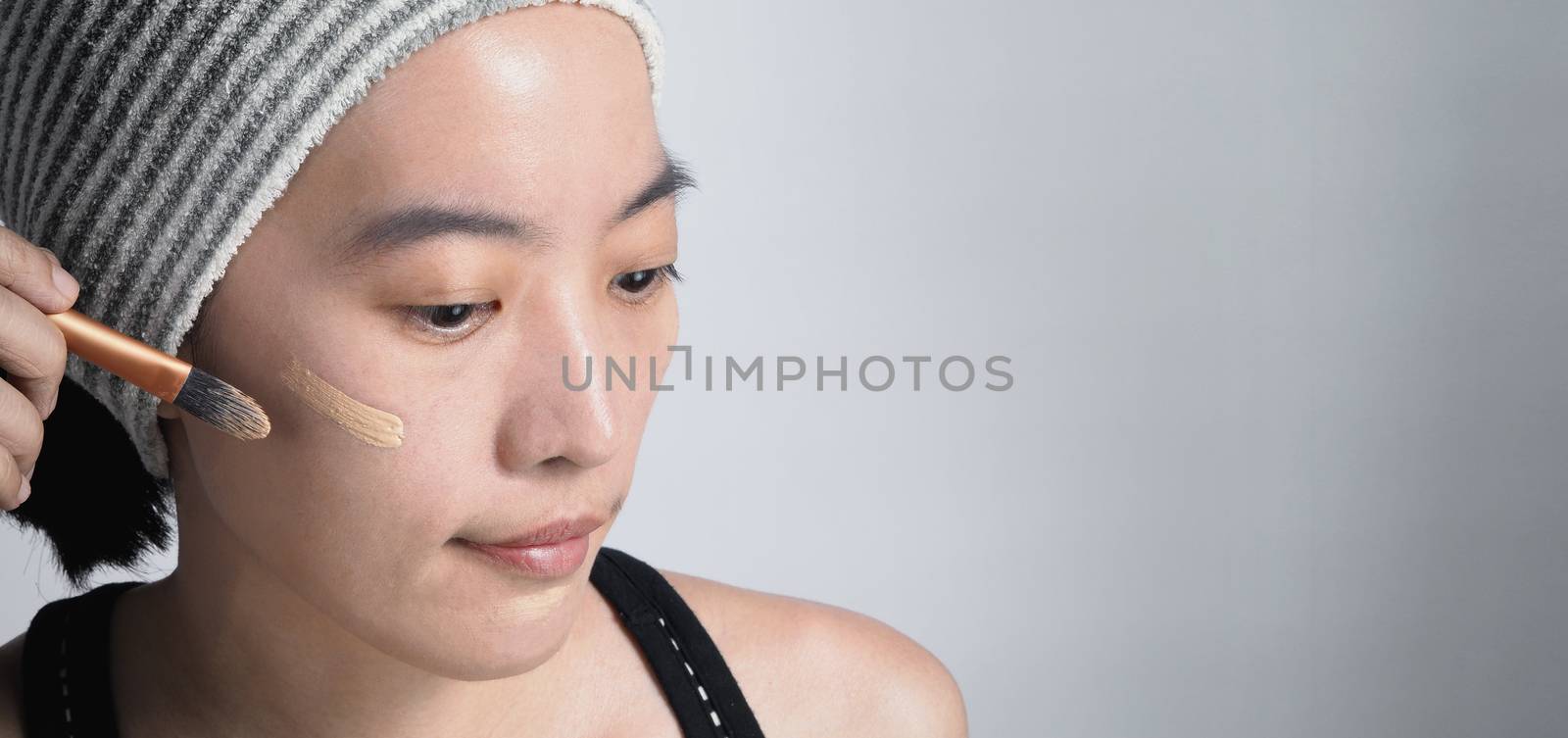 Asian girl or woman 40 years old beautiful face with japanese look making up by foundation liquid and cosmetic brush on sensitive skin for helping her complexion look flawless and no retouch.
