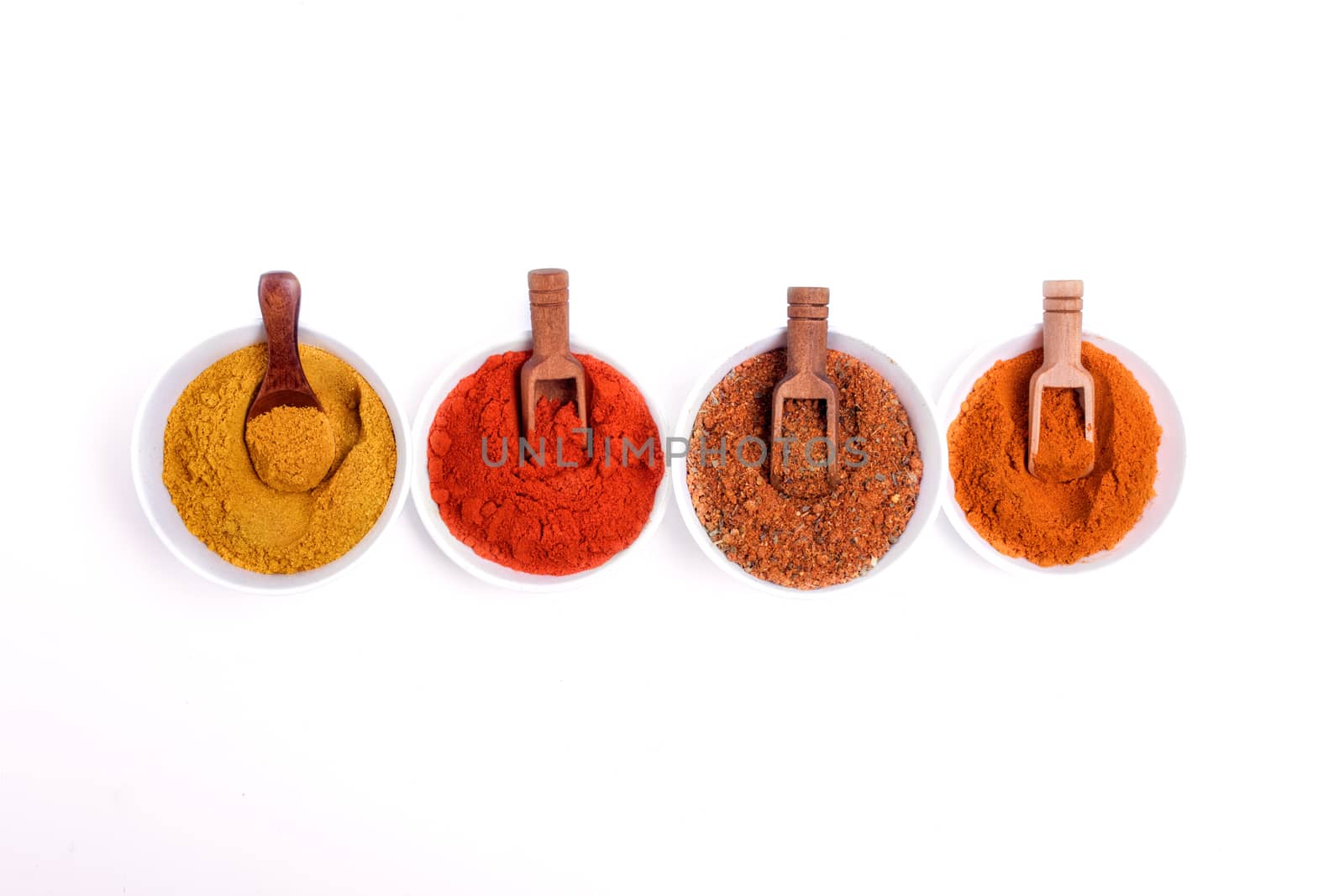 Colorful spices and wooden spoon in white bowl on white background