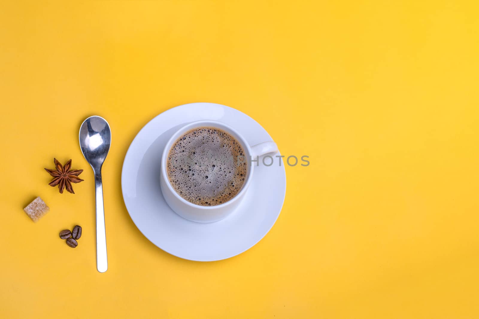 a cup of coffee, spoon, coffee beans, sugar, anis on yellow background