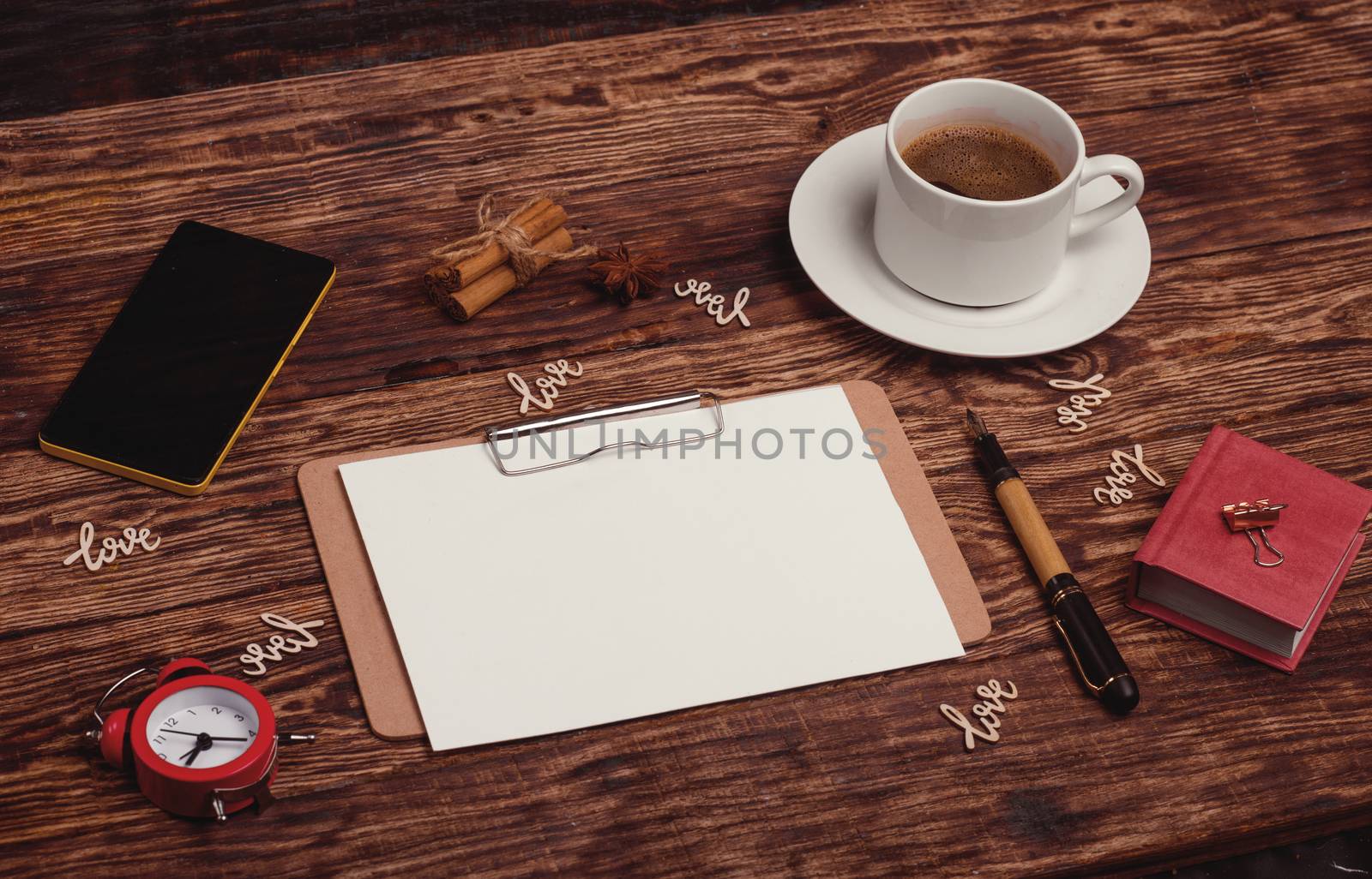 a cup of coffee, notebook, ink pen, phone and wooden words Love on wooden background