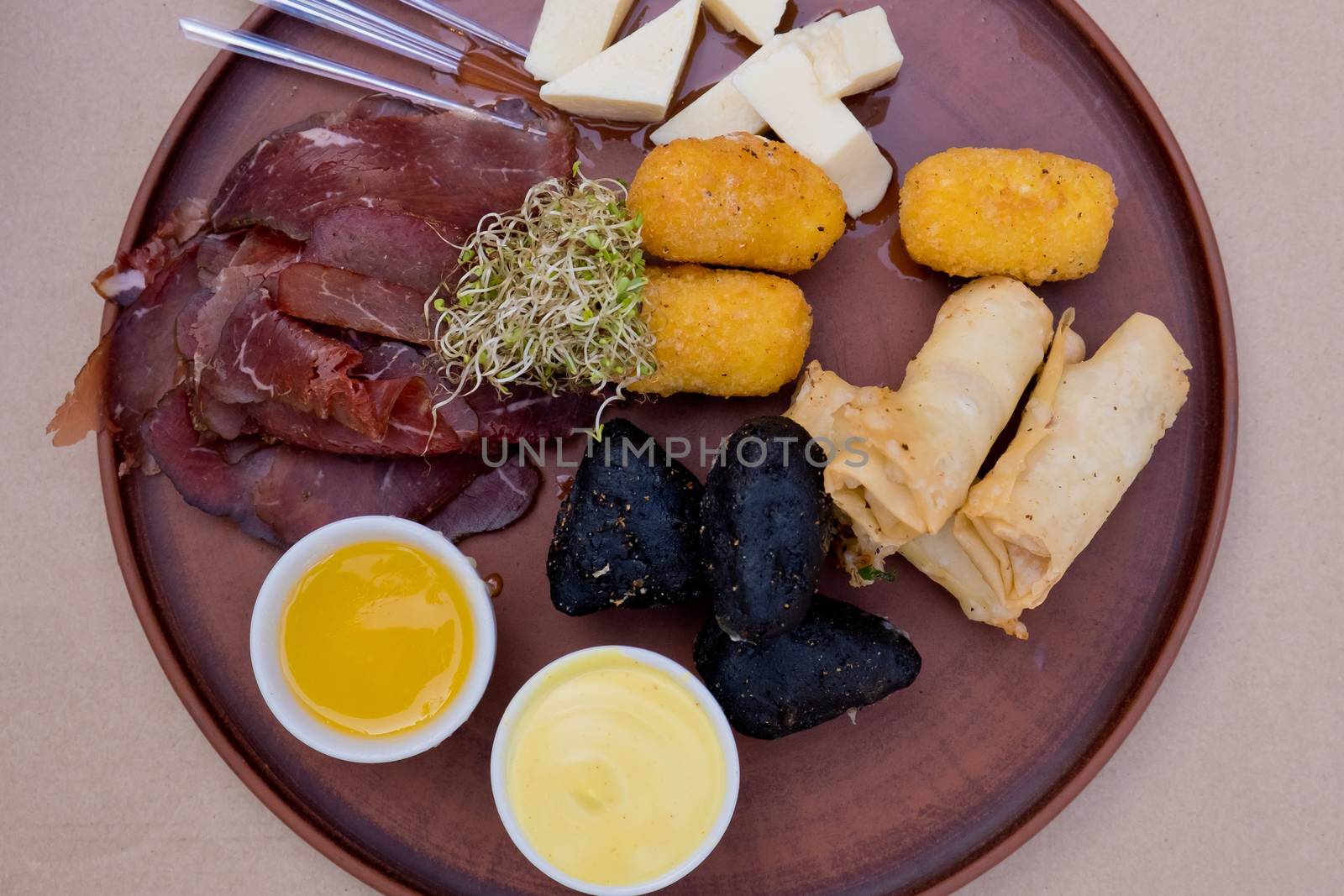 Beer snacks on a clay plate: bastruma, feta cheese, cheese in batter, honey and mustard.