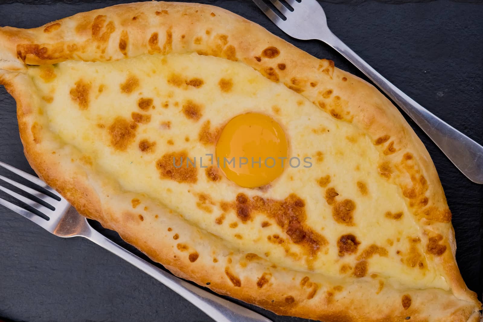 Georgian dish khachapuri with egg in the center. Soft focus. Closeup. Top view.