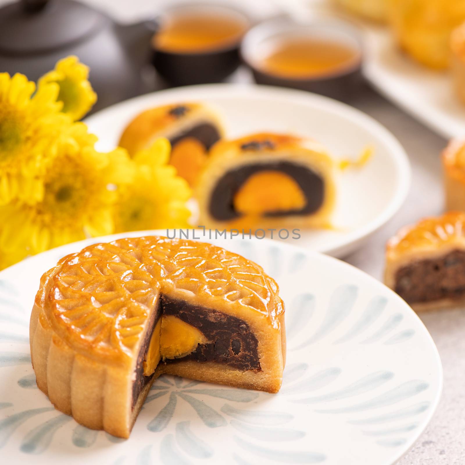 Tasty baked egg yolk pastry moon cake for Mid-Autumn Festival on bright cement table background. Chinese traditional food concept, close up, copy space.